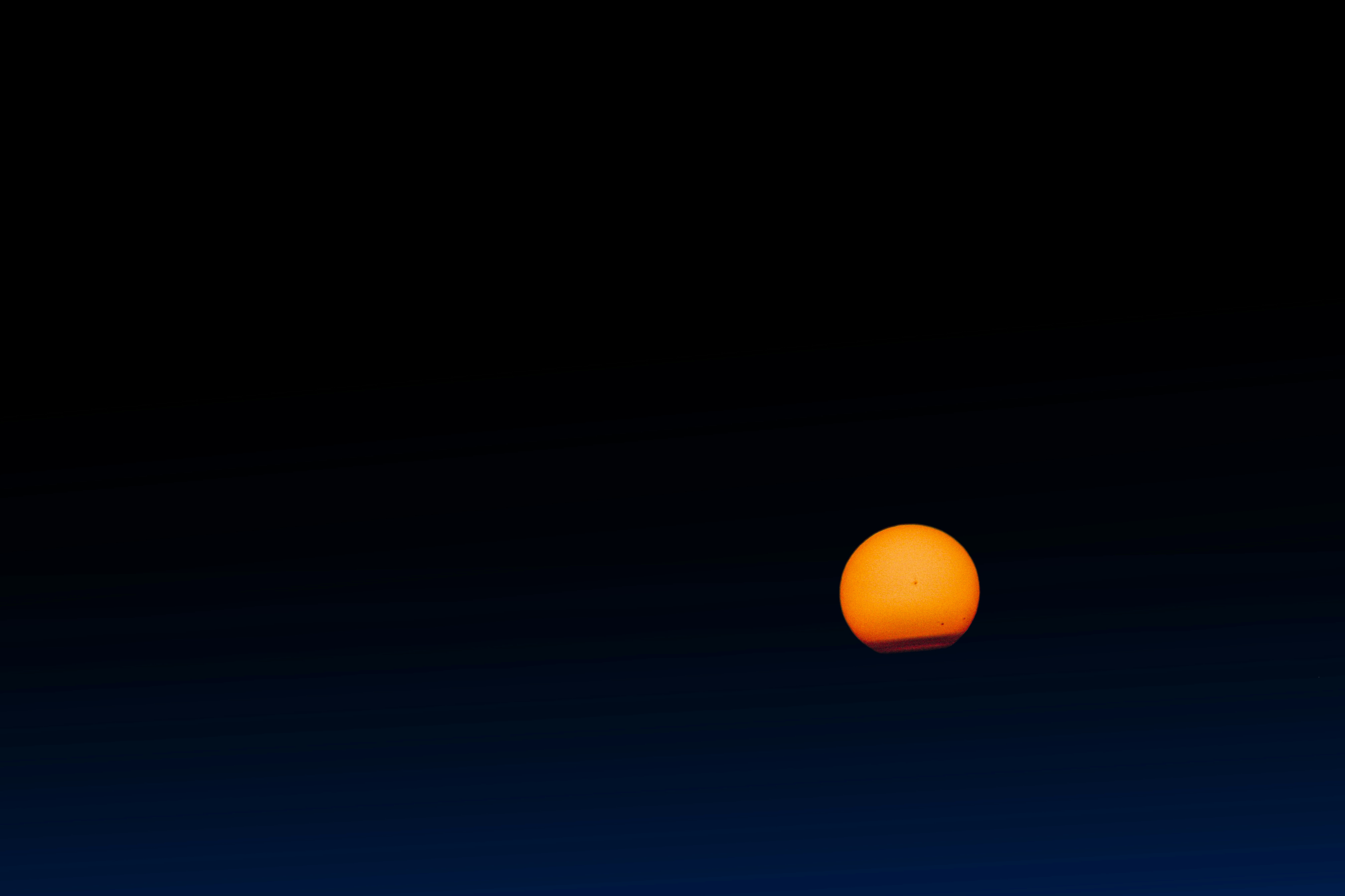 An orange sun setting against a dark blue sky.
