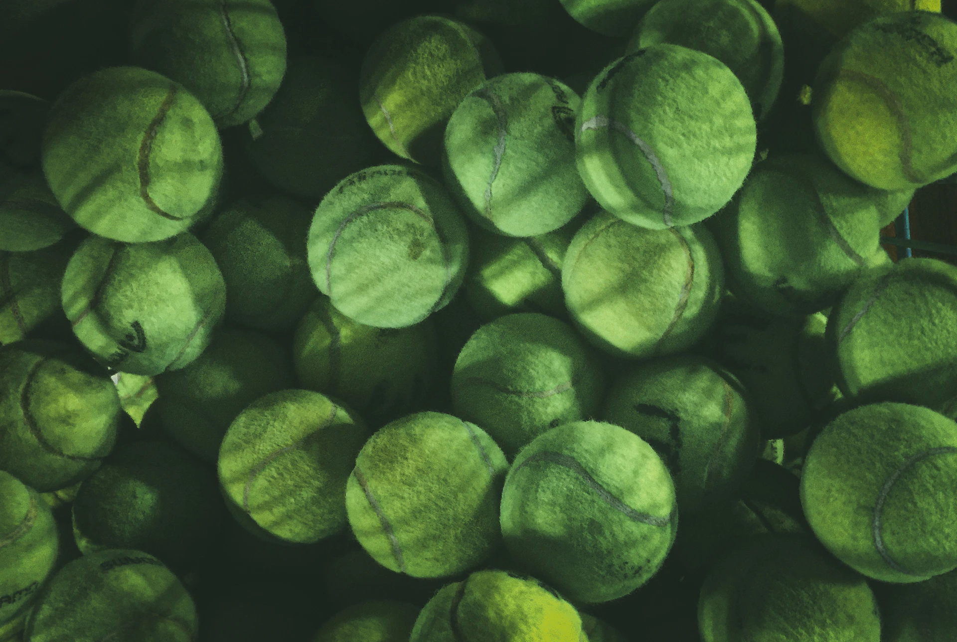 Numerous green tennis balls with visible seams