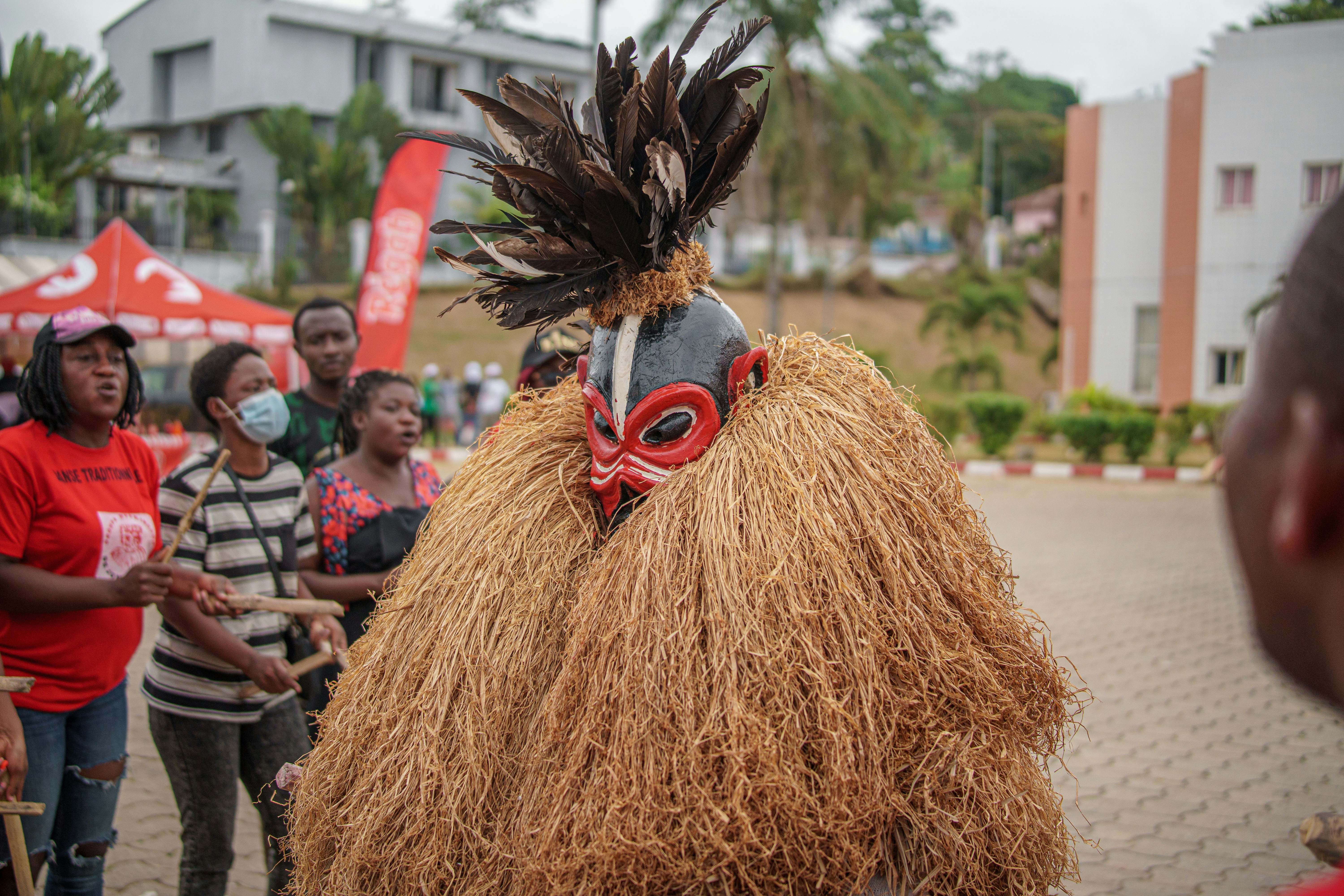 A person in a vibrant traditional feathered and straw costume.