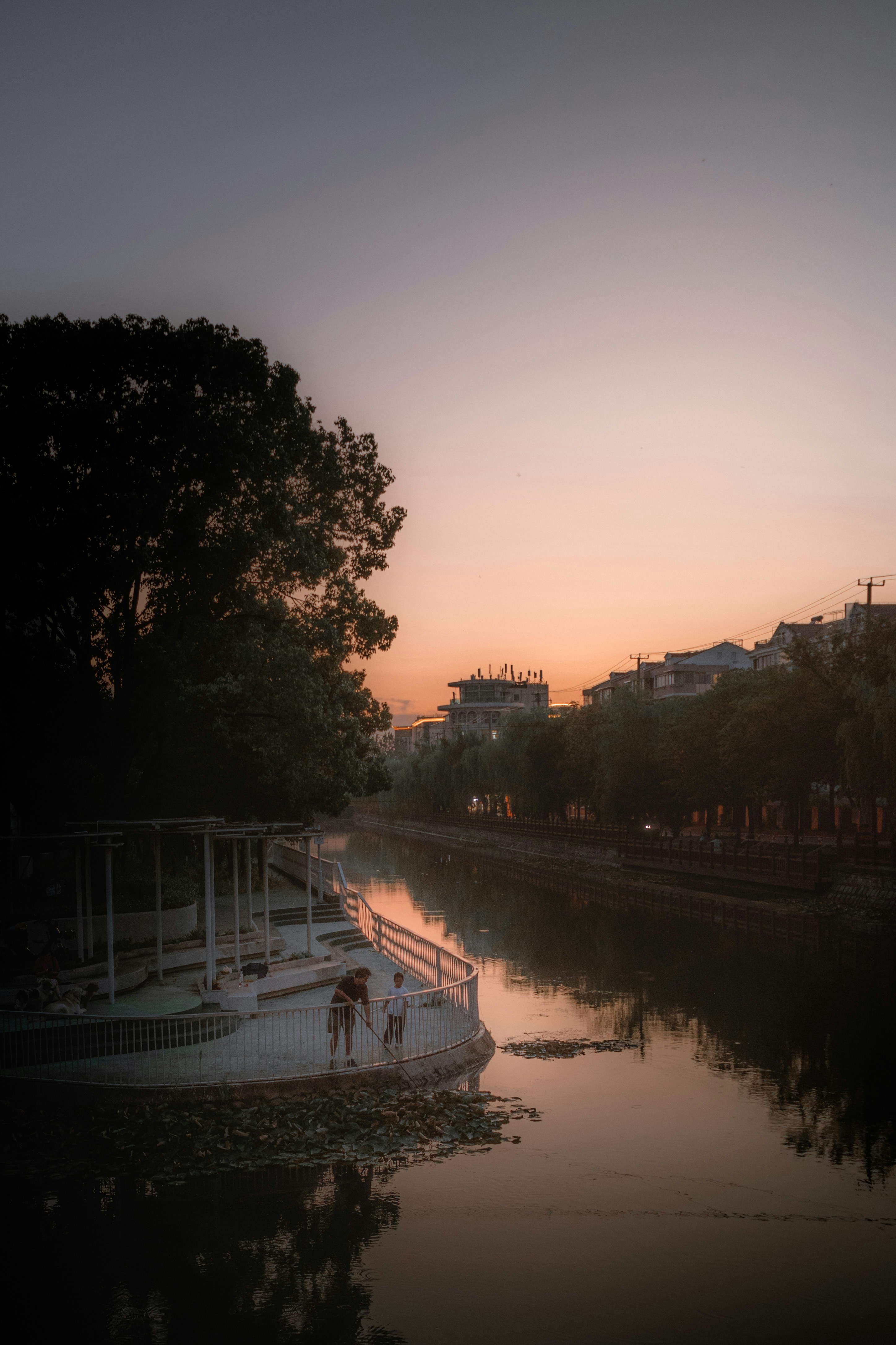 People on a pier by a river at sunset