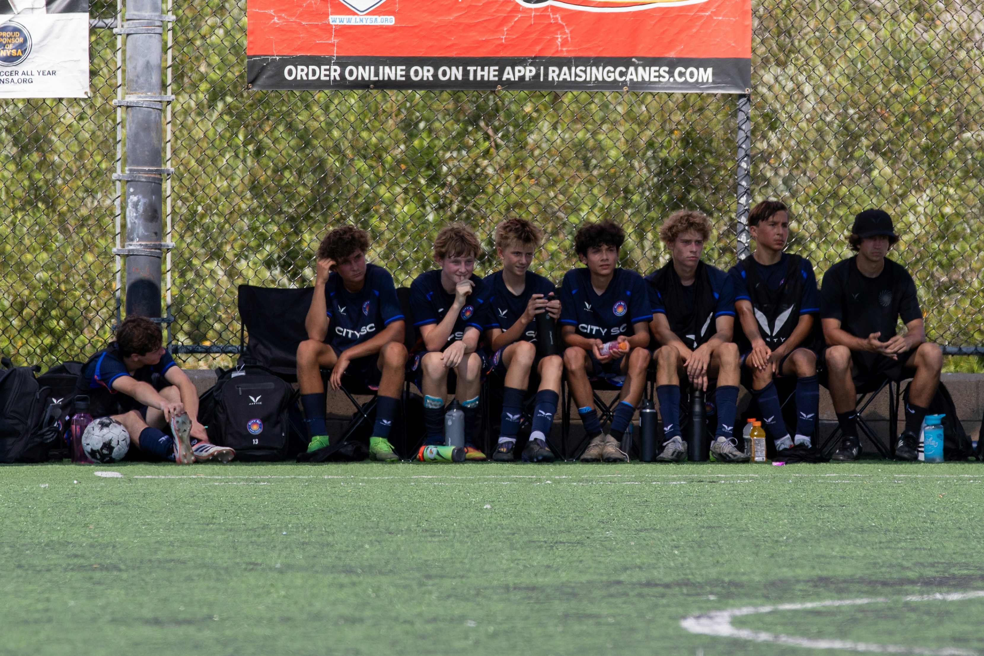 Young soccer players sitting on the bench during a game.