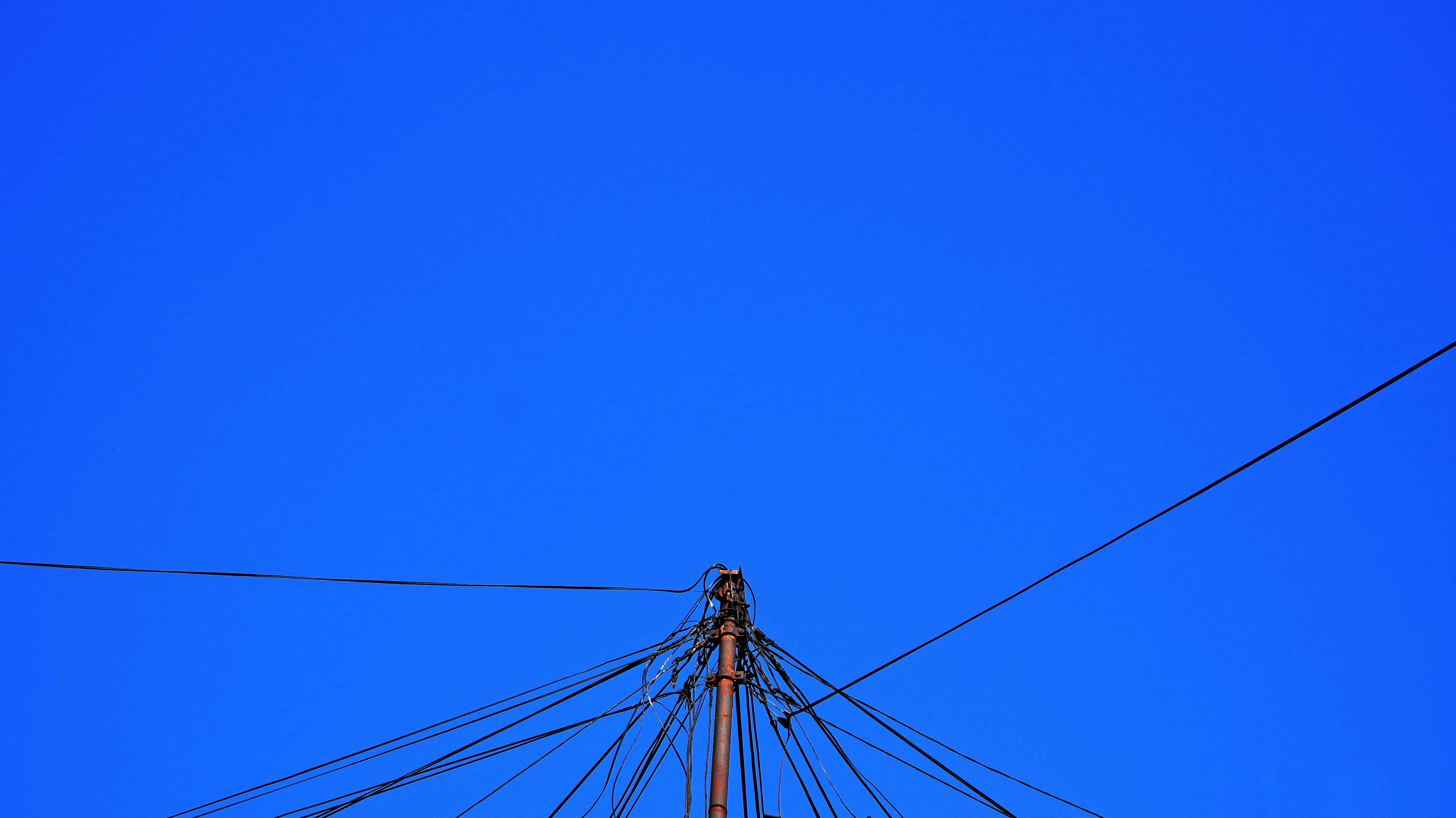 電柱と絡まった電線が澄んだ青空を背景に。