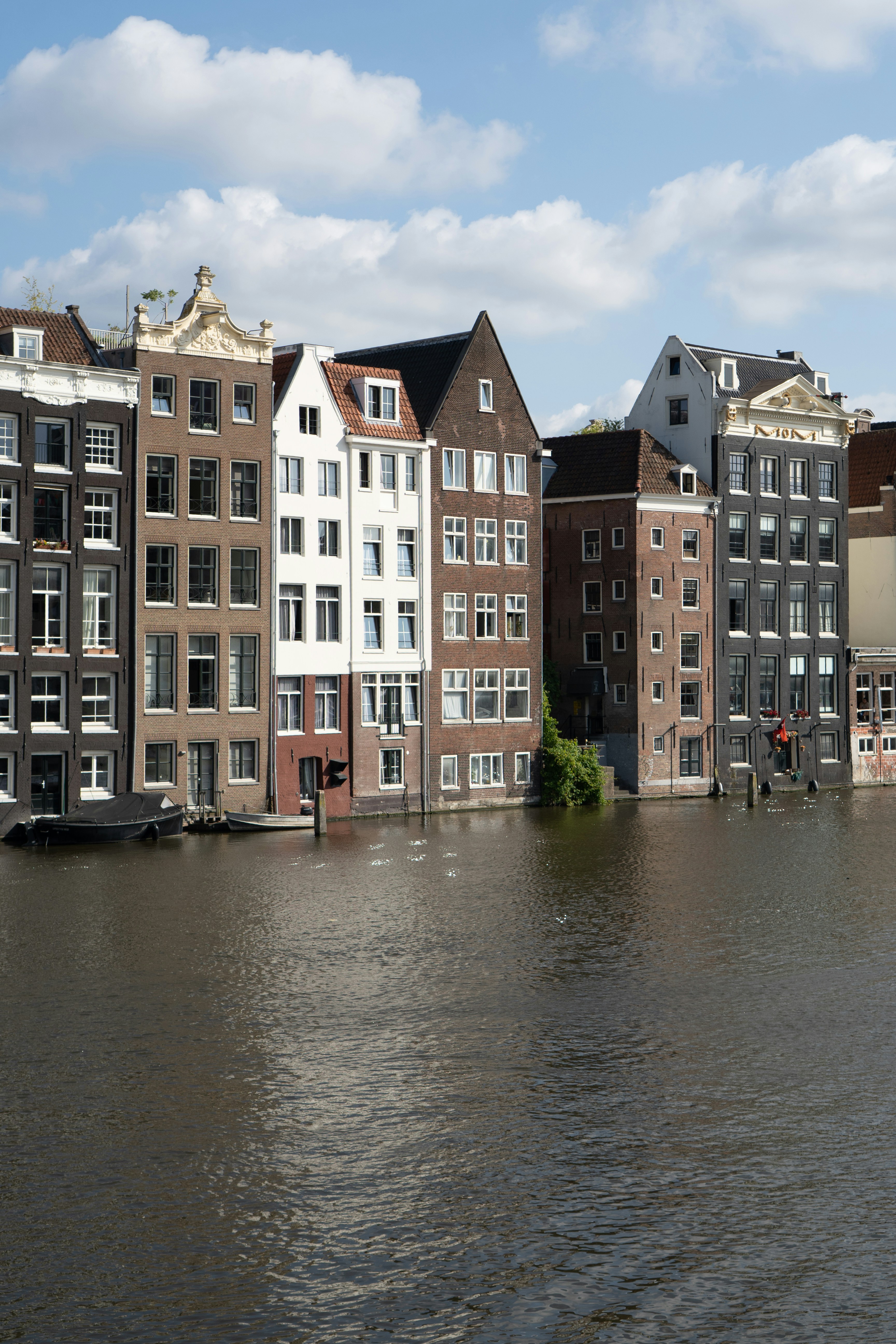 Historic canal houses line a waterway under a blue sky.