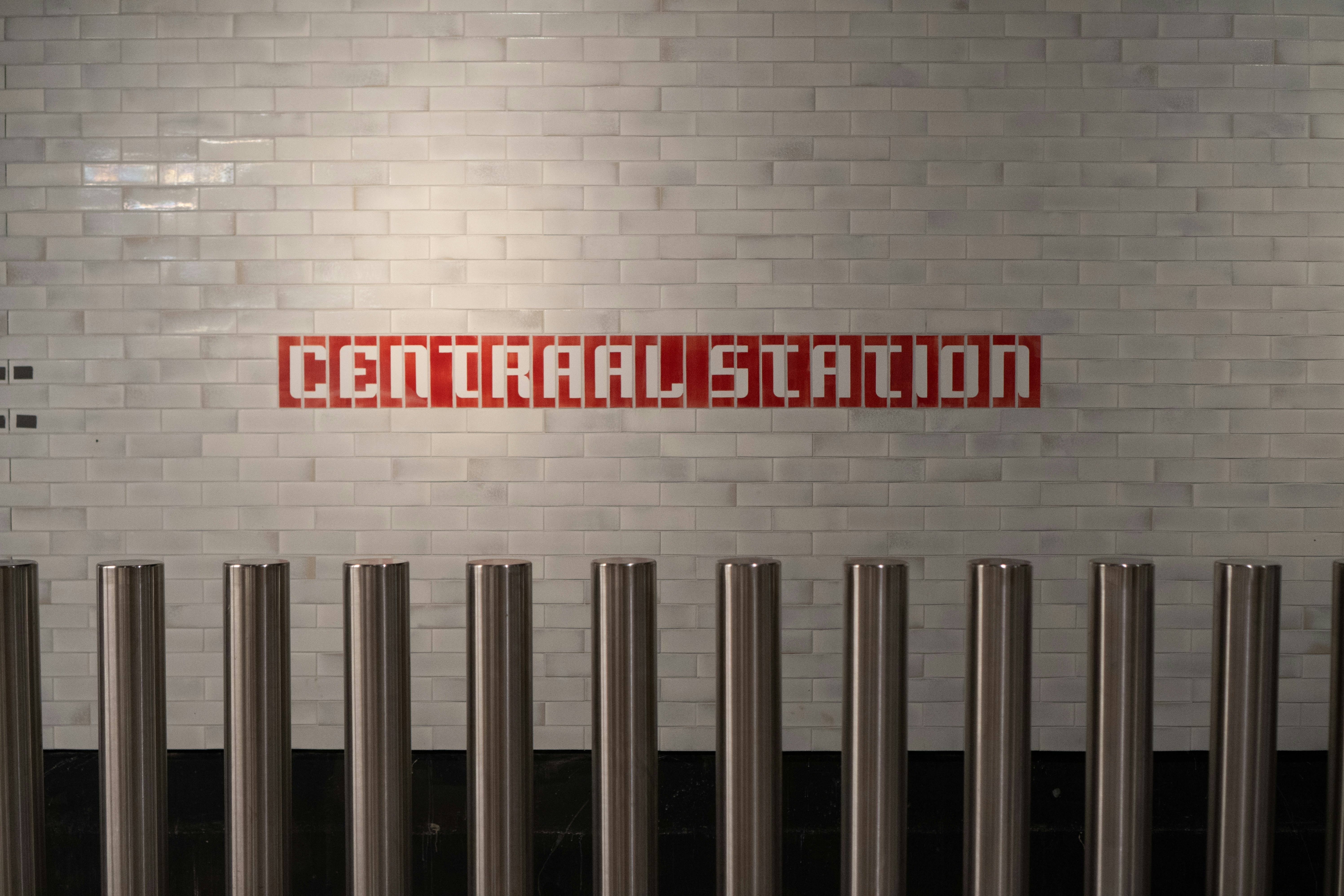 Central station sign on brick wall with metal barriers.