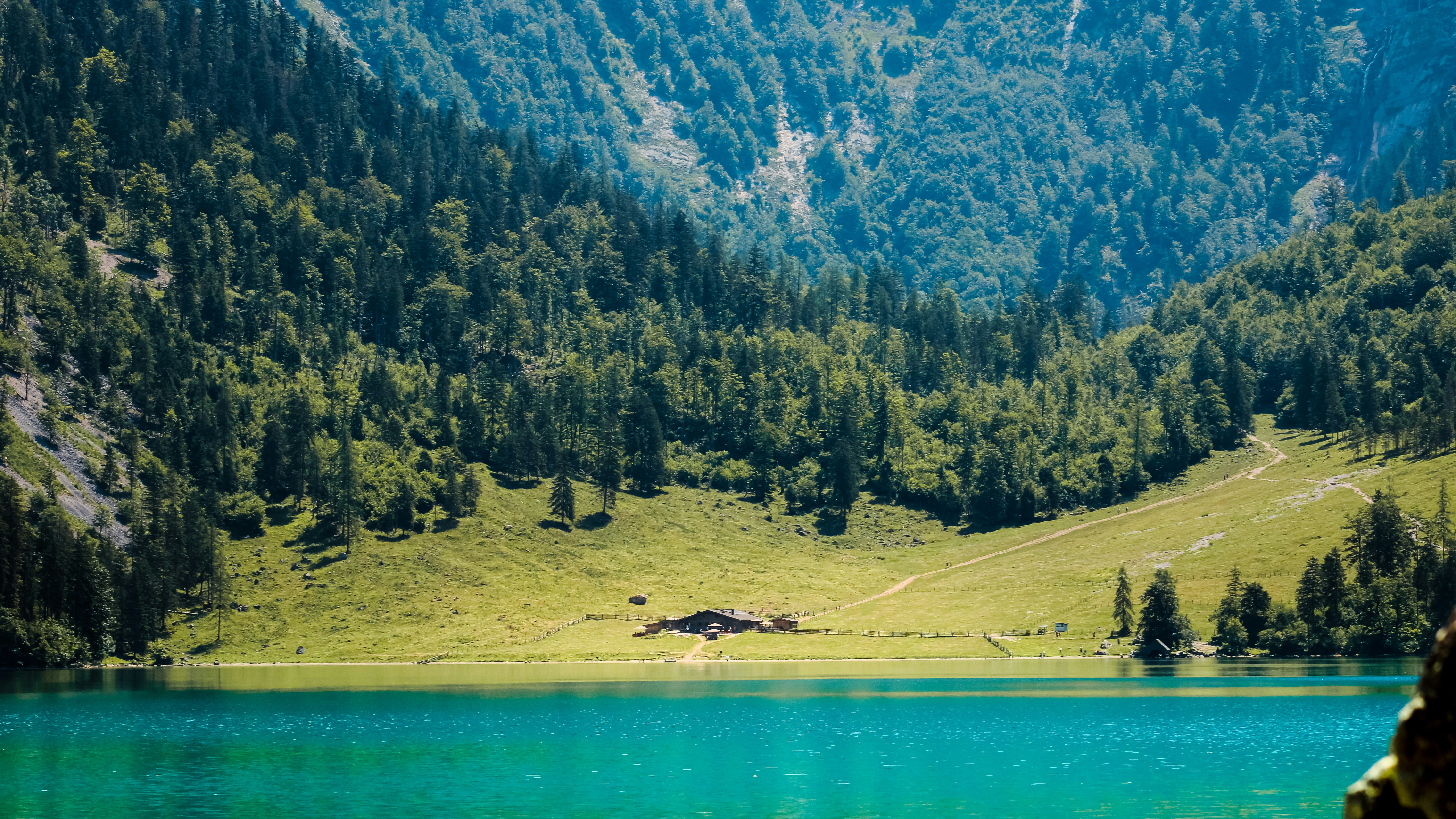 Danau berwarna turquoise dengan kabin di lembah pegunungan yang hijau.