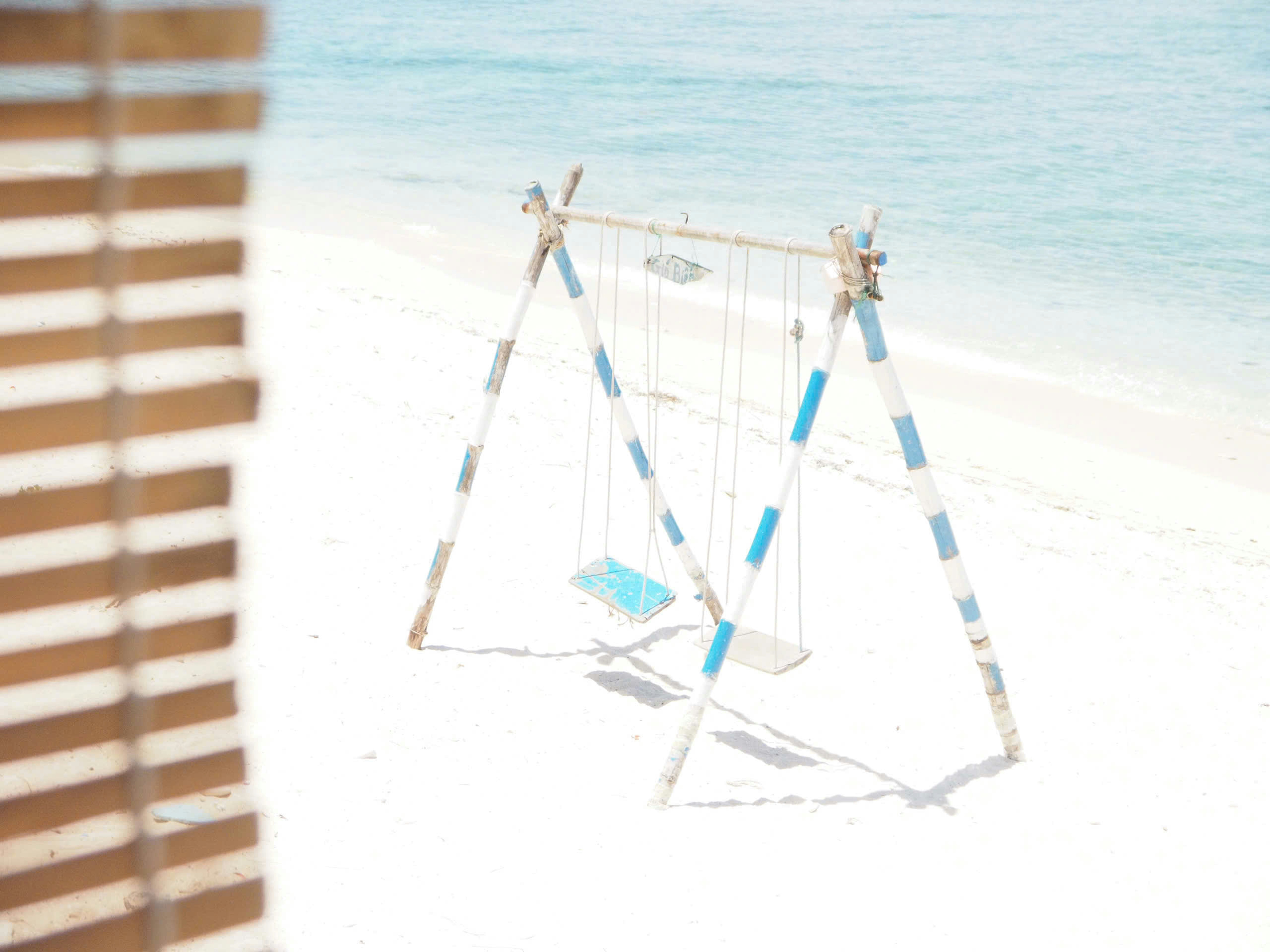 A wooden swing set on a white sand beach