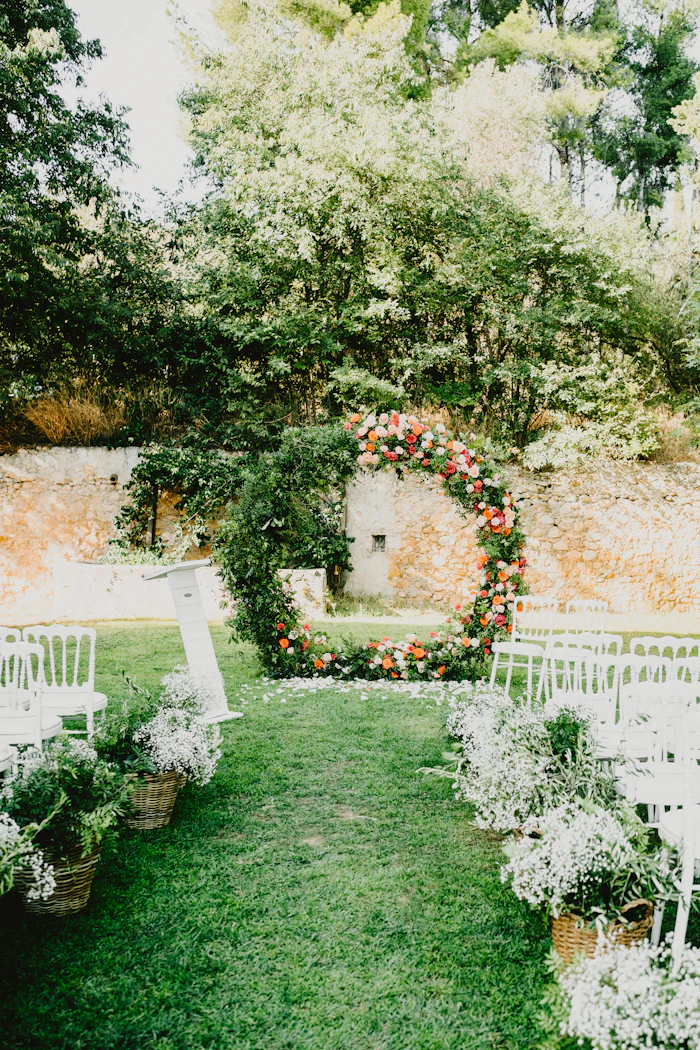 Arco de flores y sillas blancas para una ceremonia al aire libre