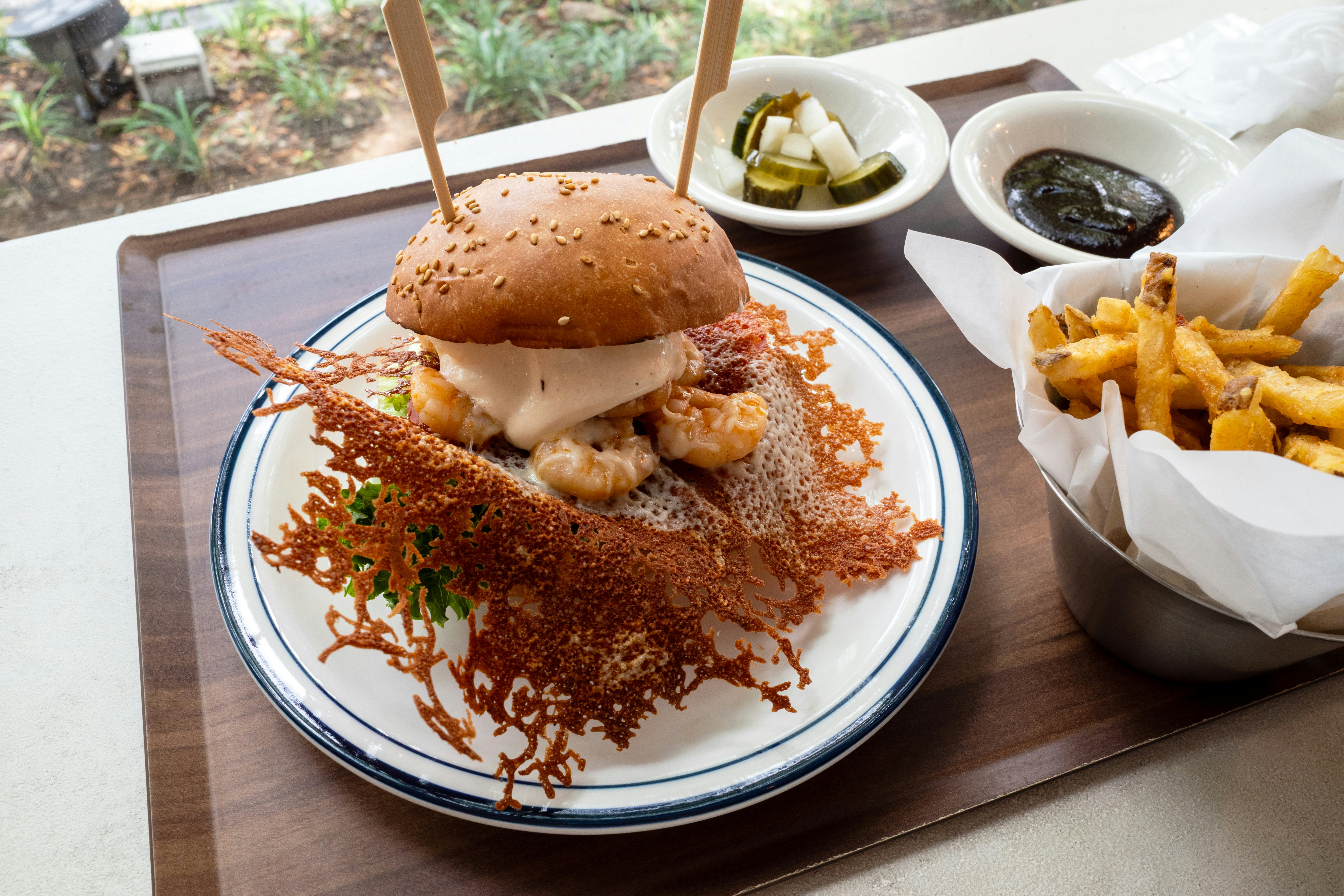 Shrimp burger with cheese crisp, fries, and pickles