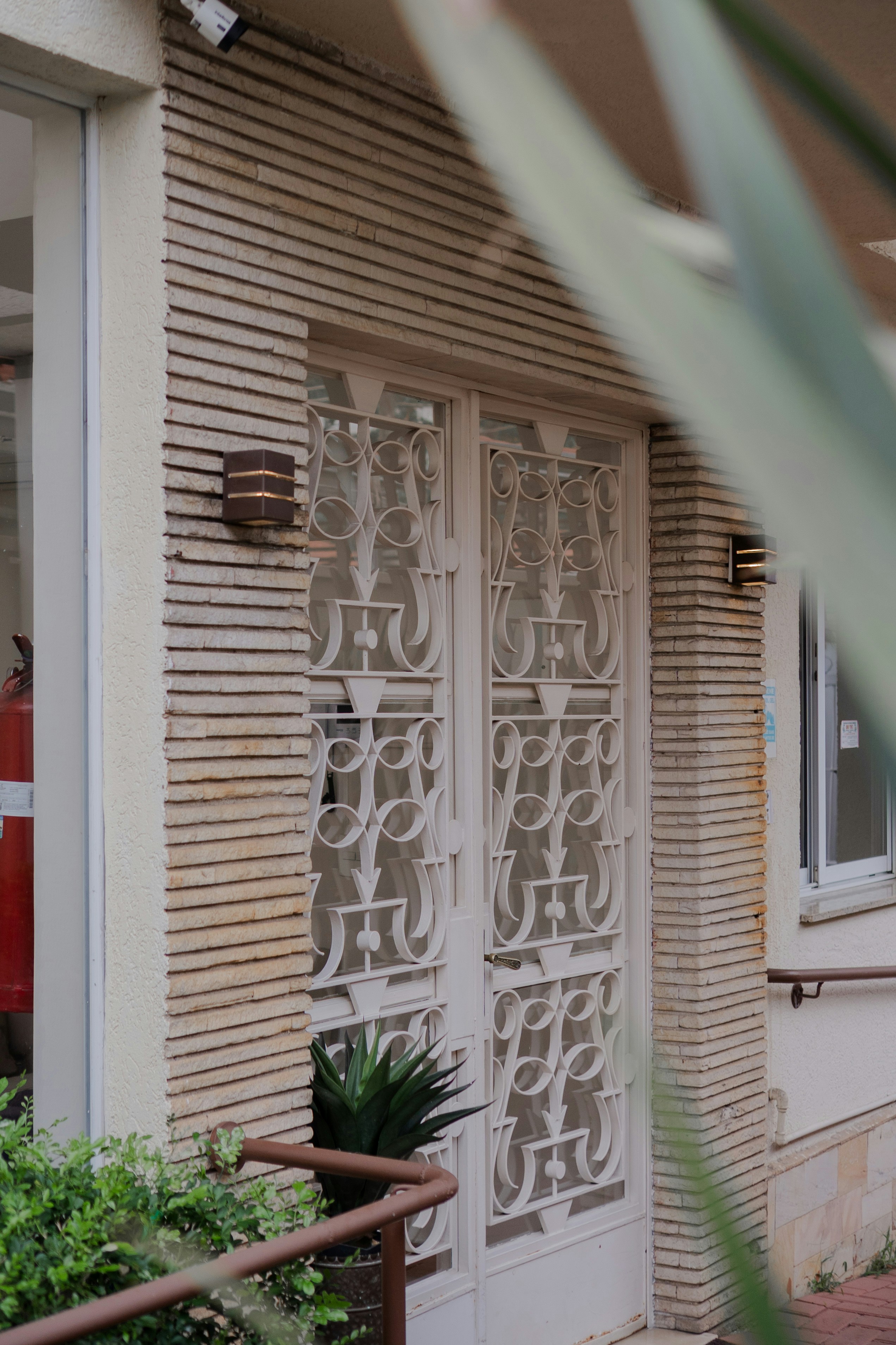 Ornate white double door with decorative metalwork and textured wall.
