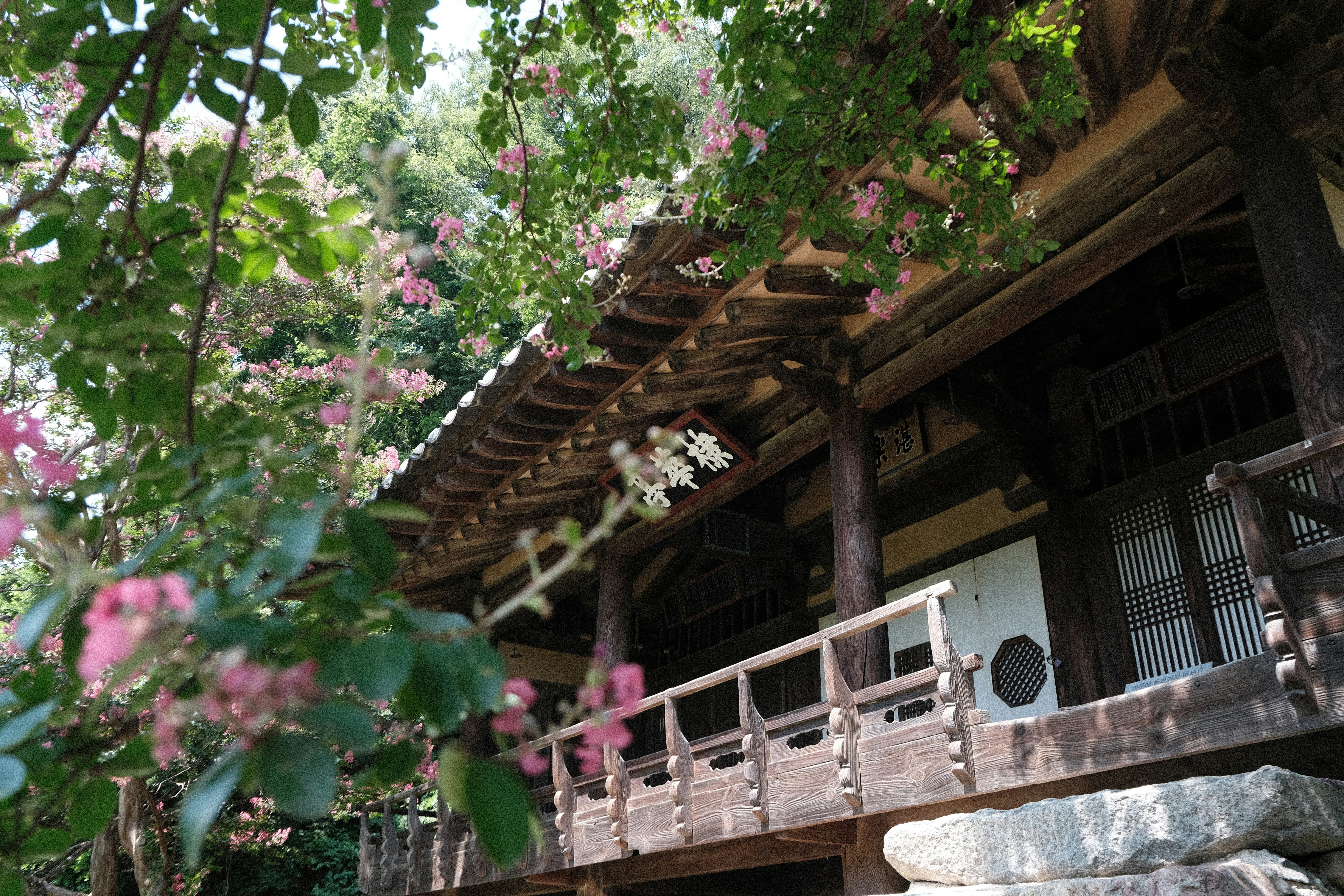 Traditional wooden building surrounded by pink and white flowers