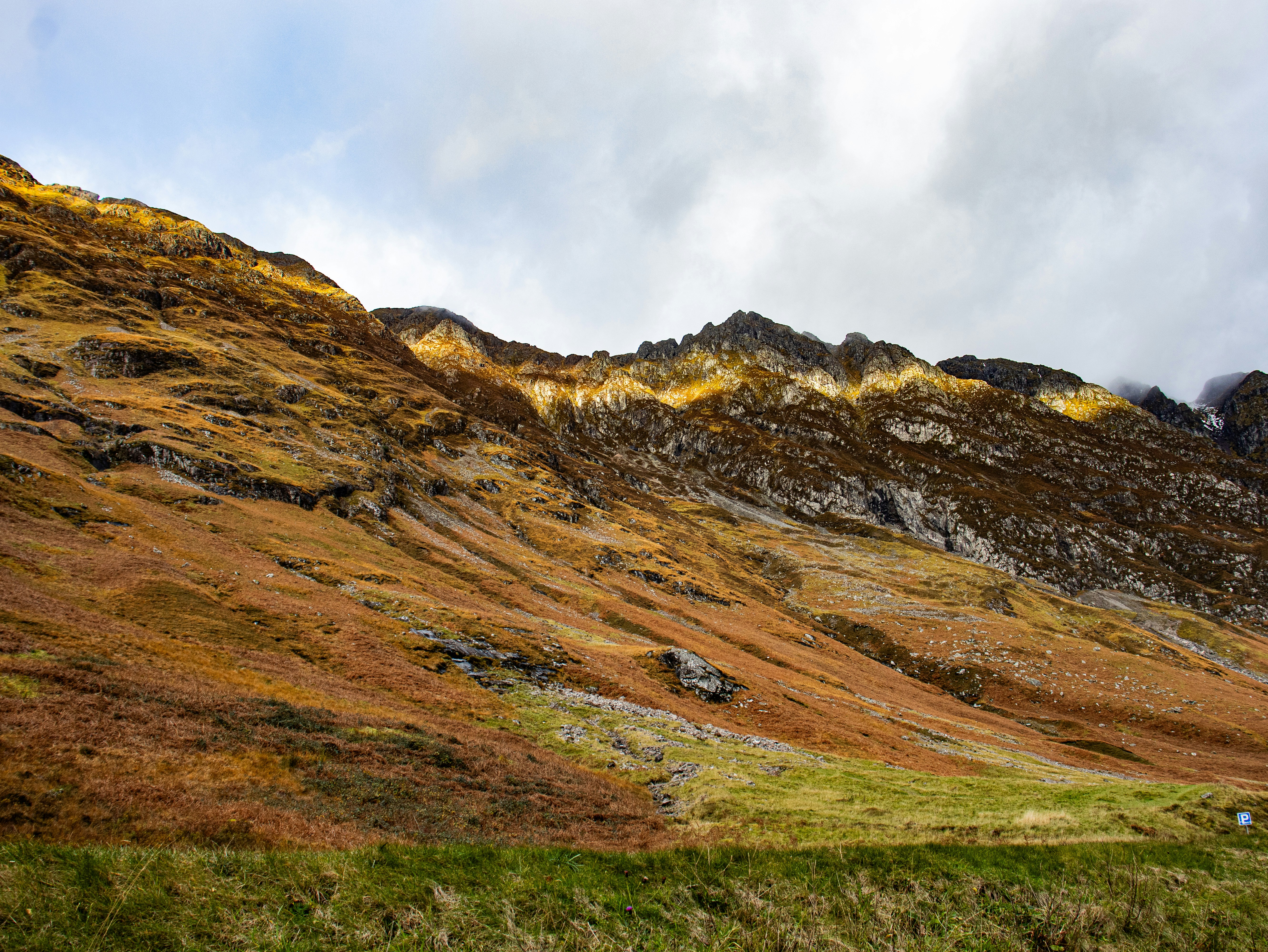 Rugged mountain landscape with autumn colors under a cloudy sky.