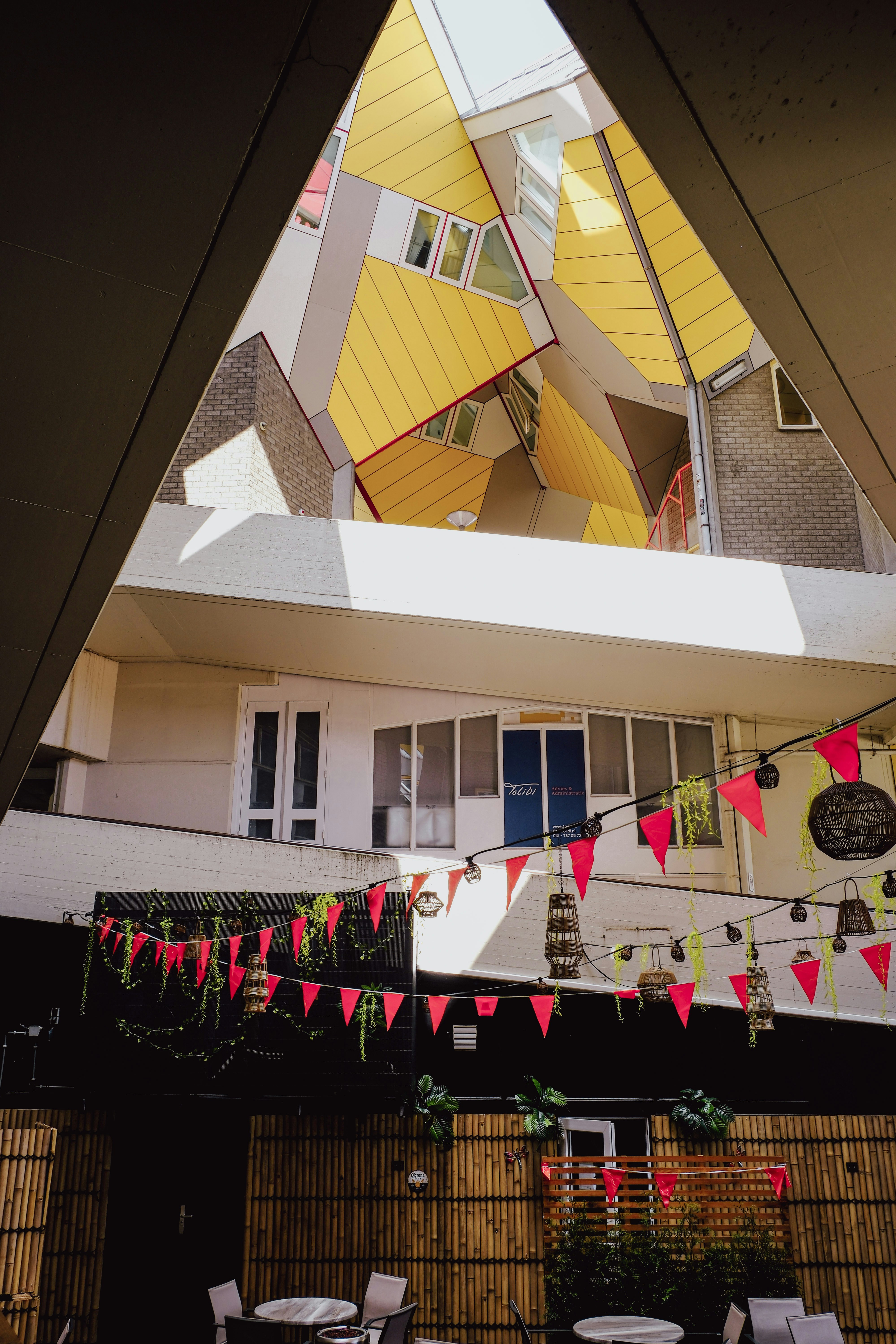 Yellow cube buildings above a courtyard with red flags