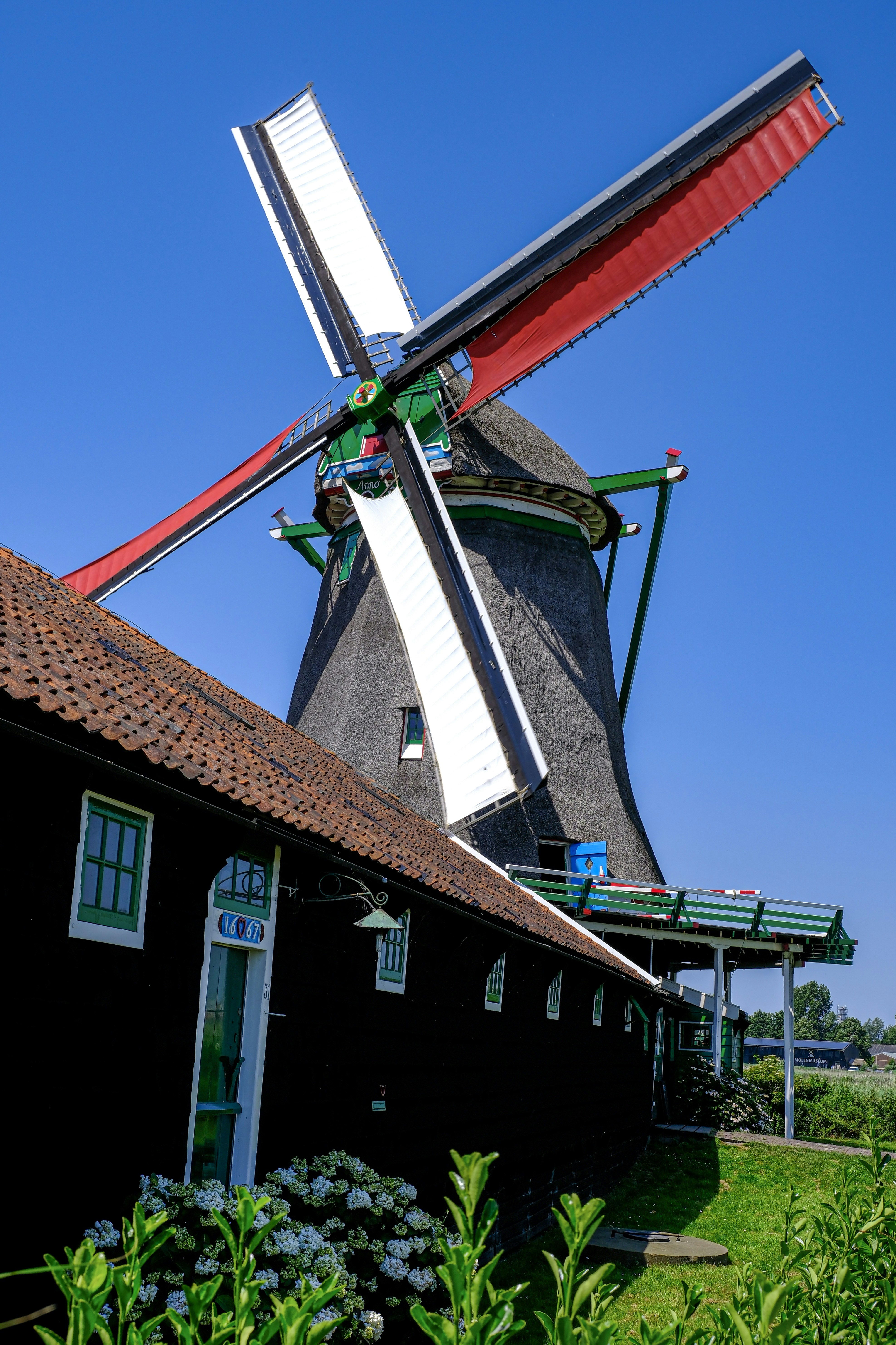 A traditional dutch windmill and building under a blue sky
