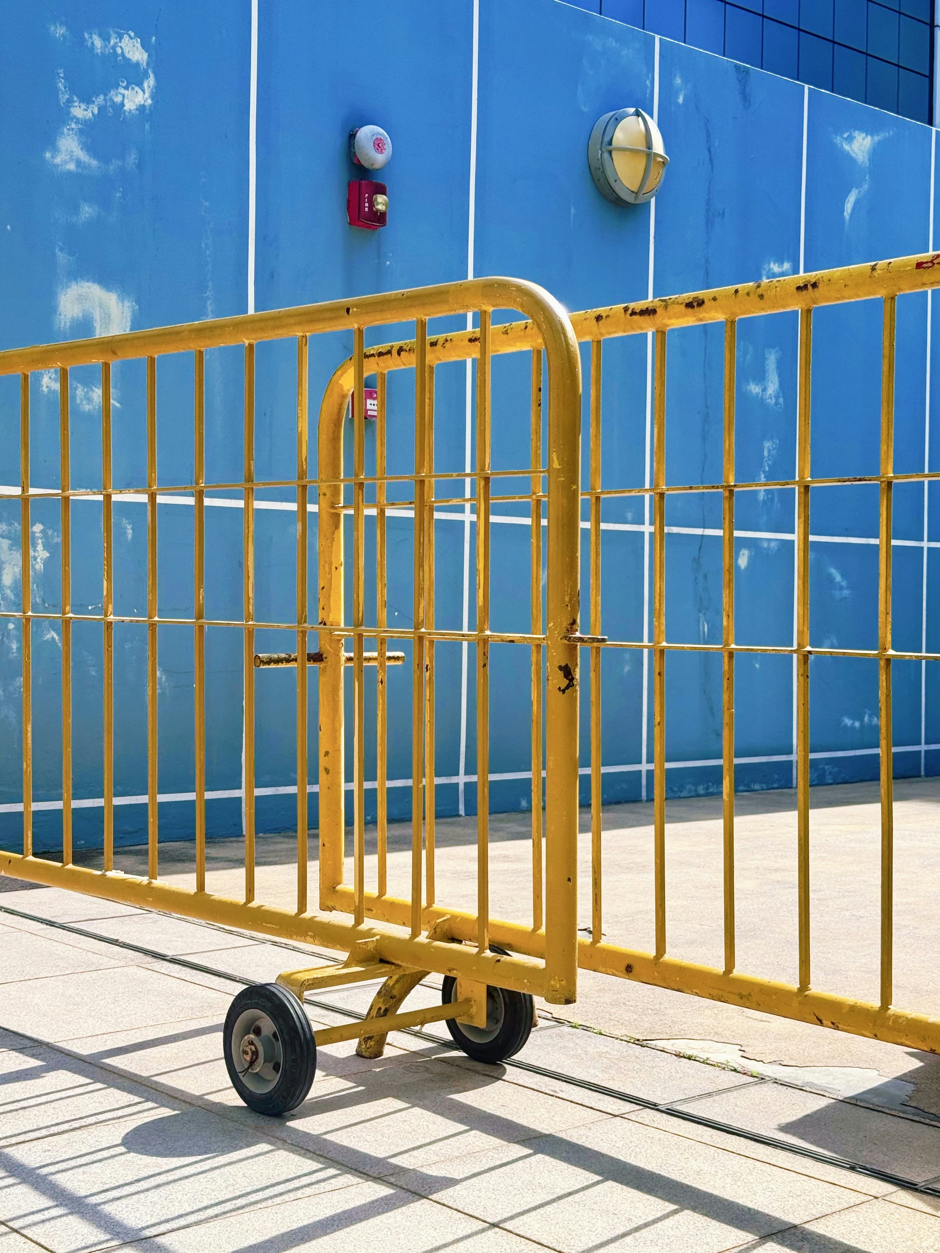 Bright yellow metal barriers against a vibrant blue wall.