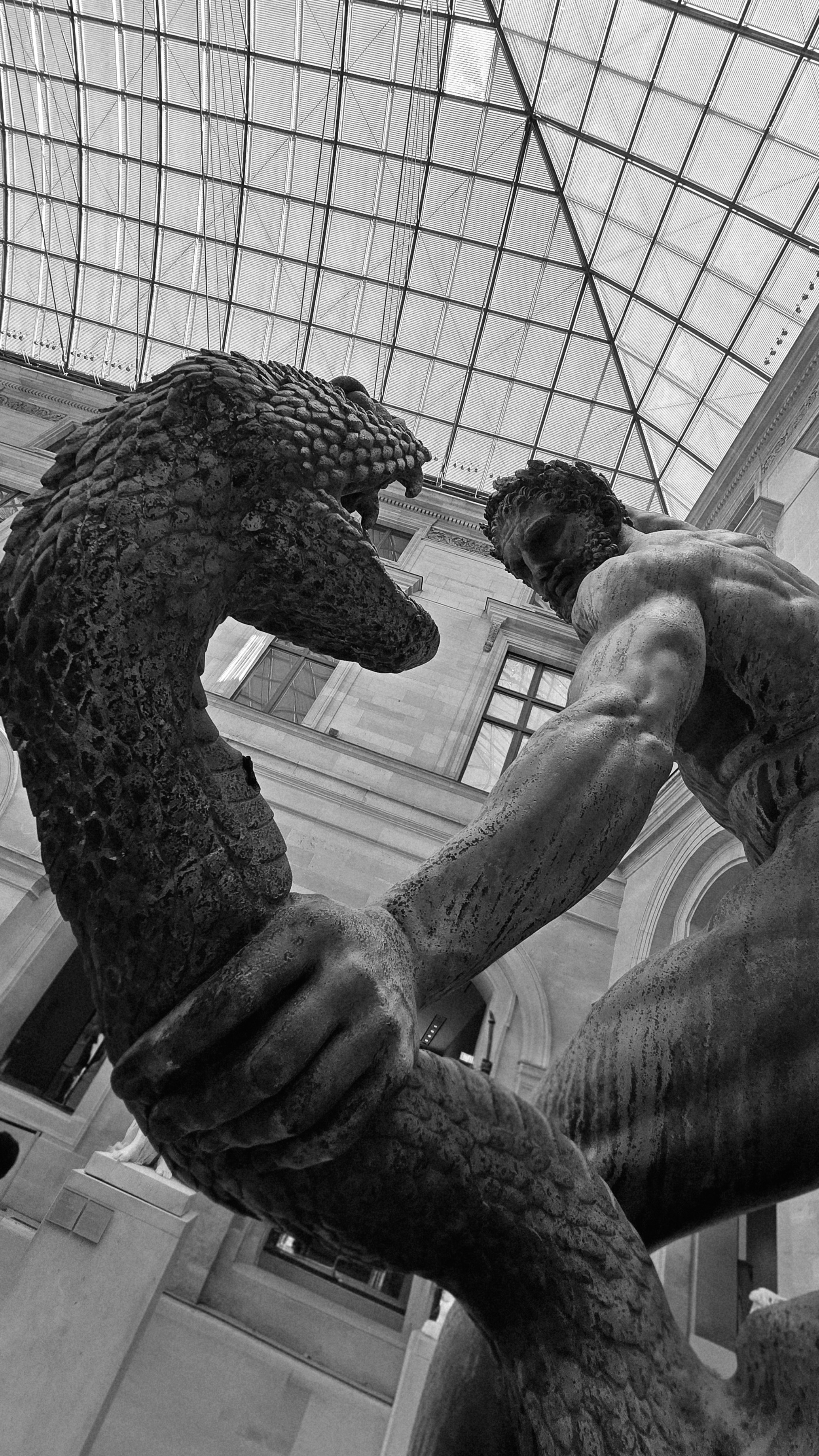 Man wrestling a large snake under a glass ceiling.