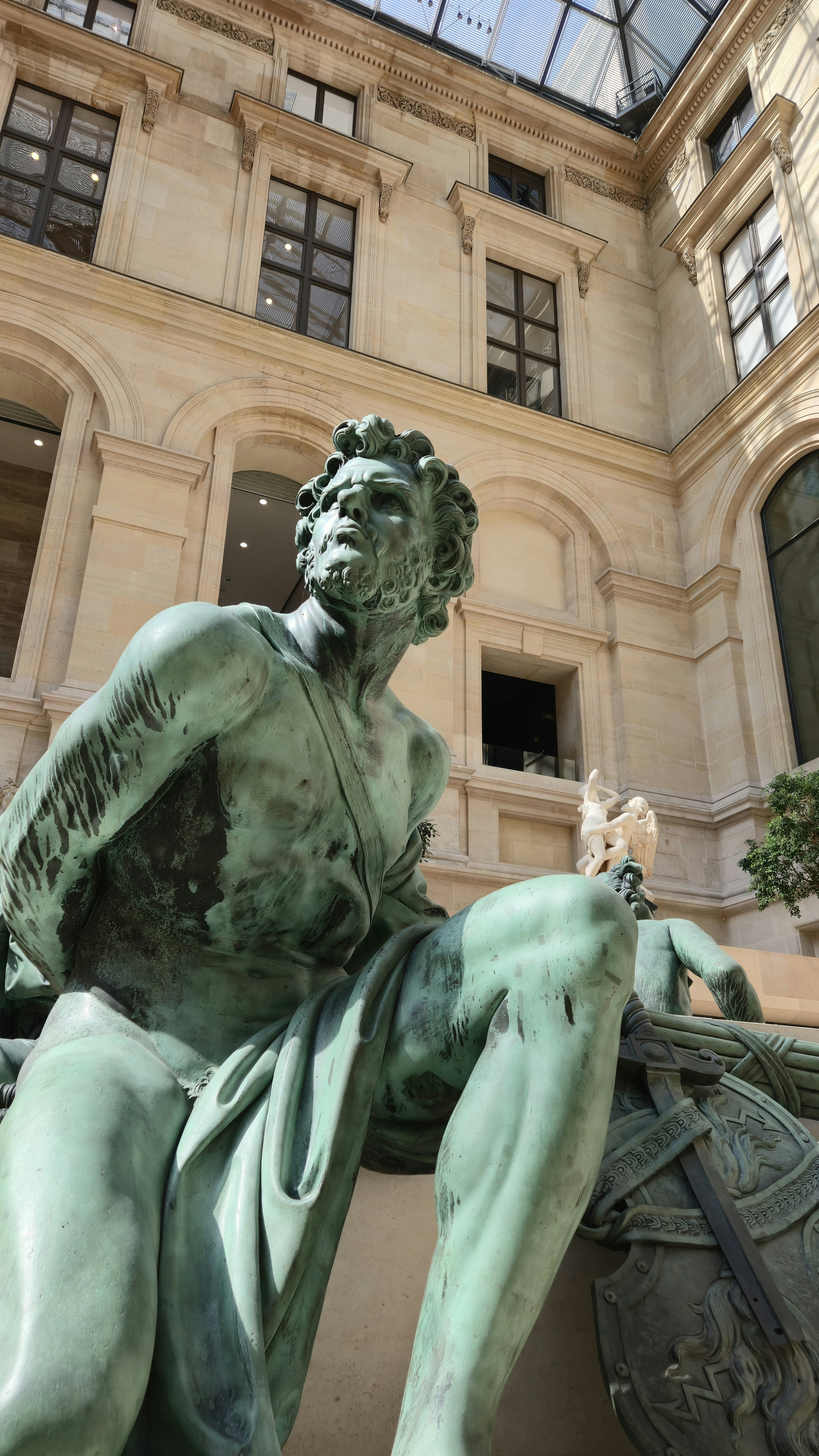 Weathered bronze statue of a man in a classical courtyard.