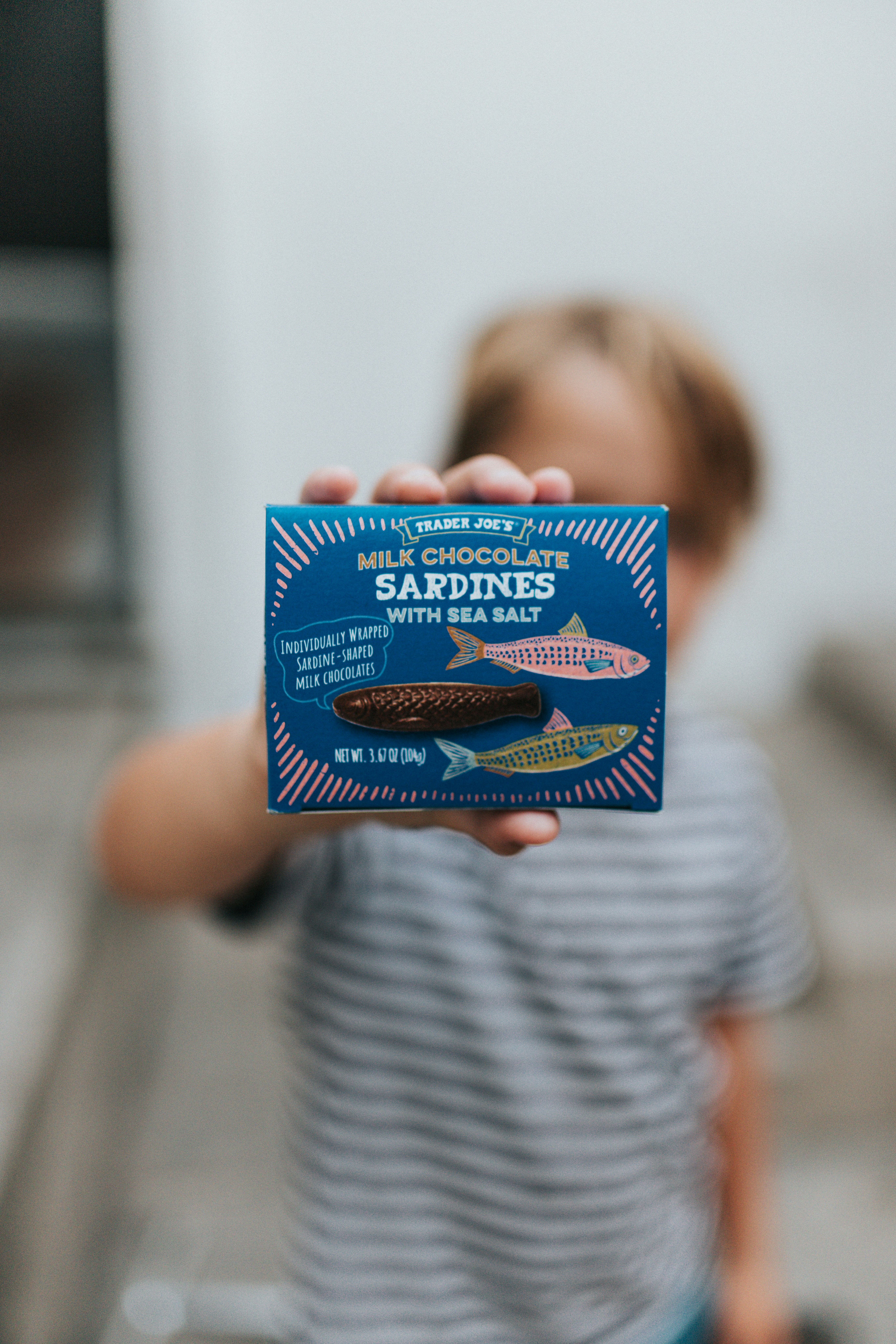 Child holds milk chocolate sardines with sea salt box.