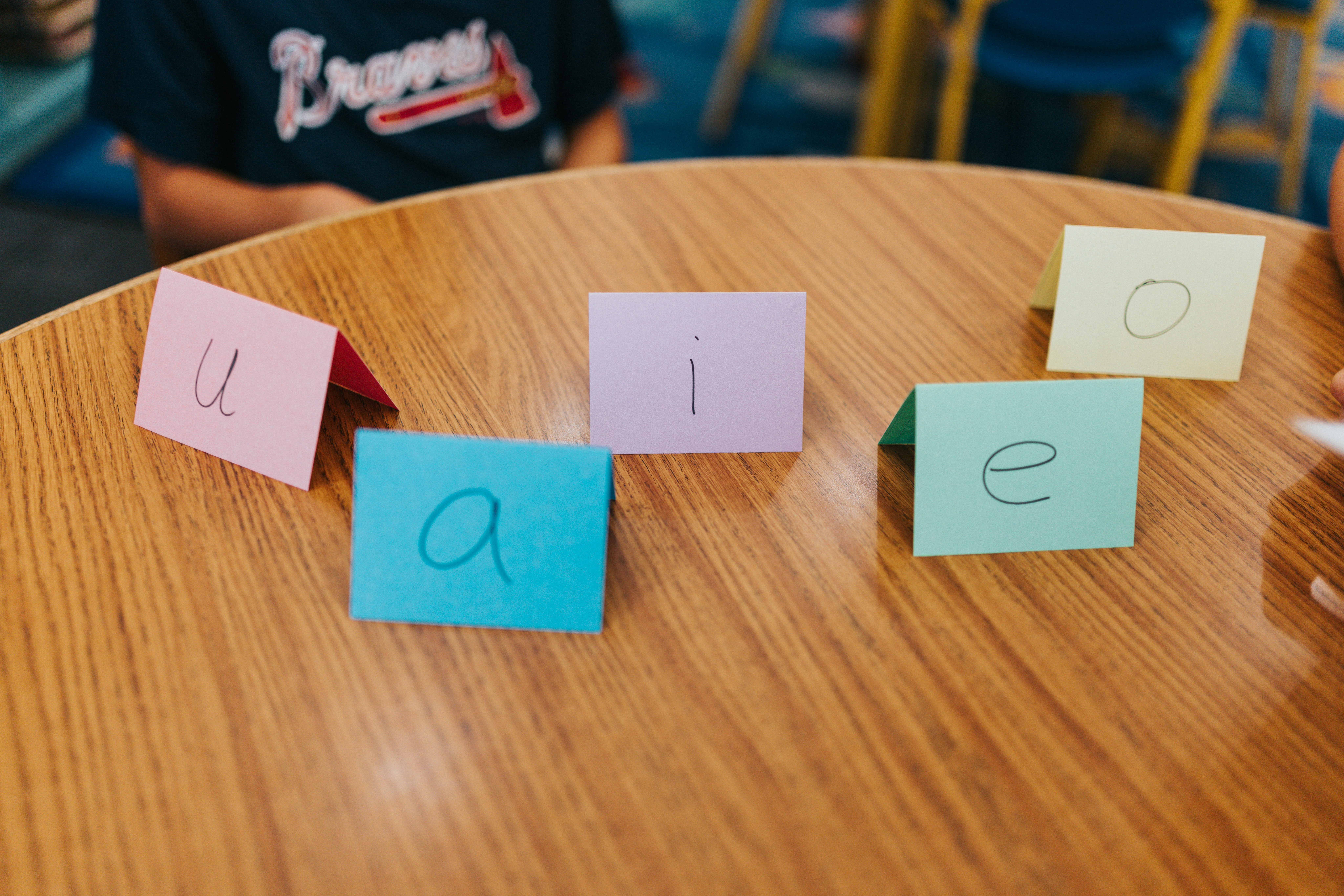 Five colorful cards with vowels on a wooden table.