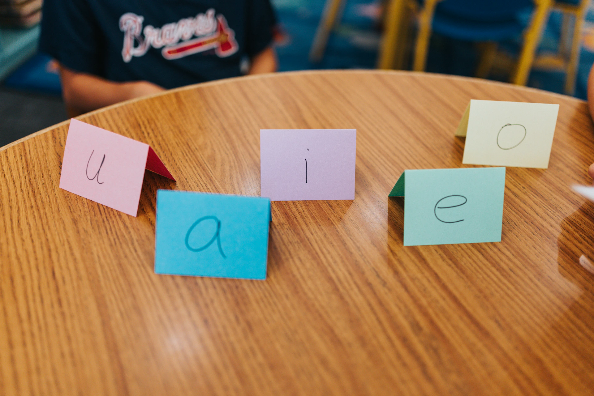 Five colorful cards with vowels on a wooden table