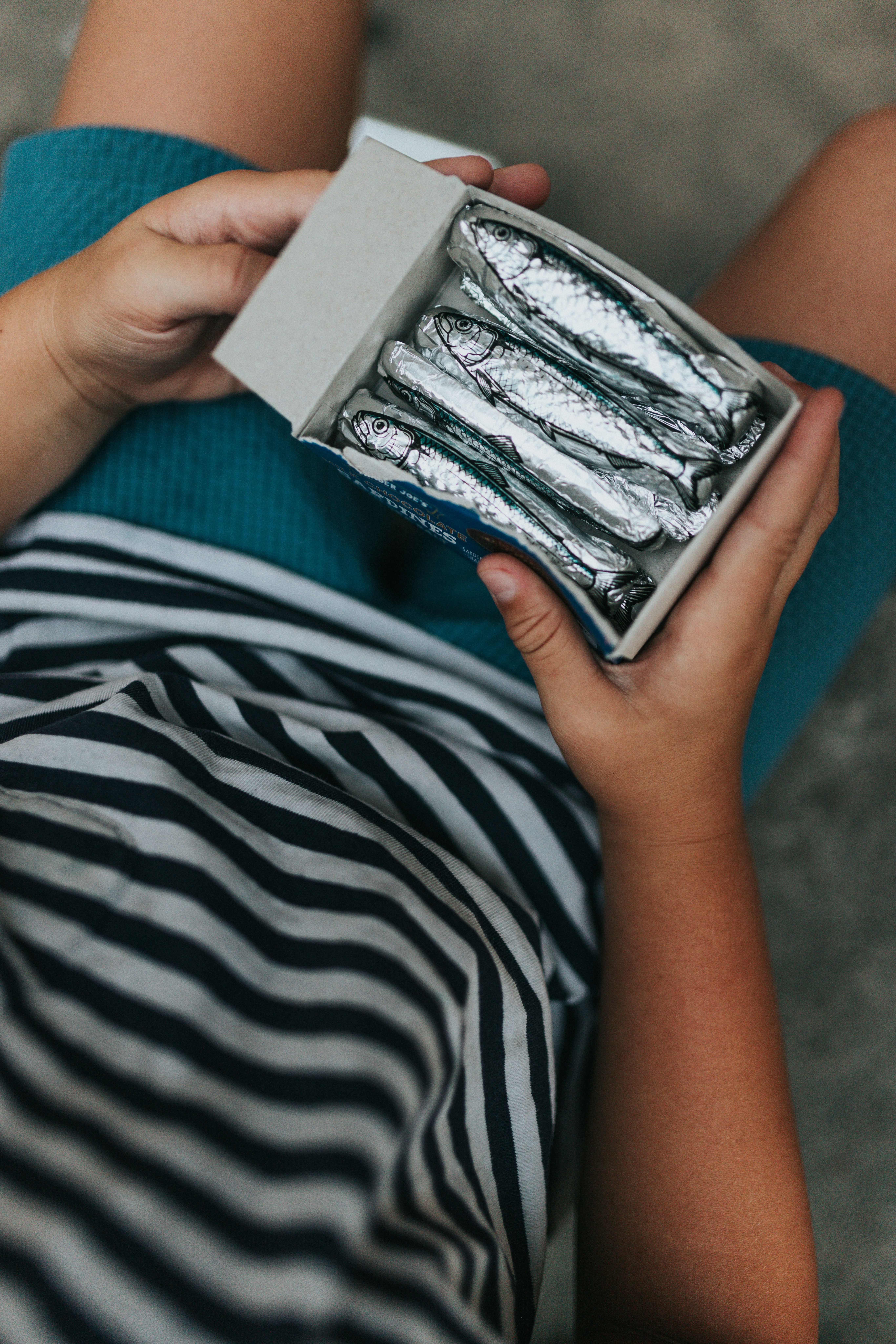 Person holding an open box with foil-wrapped items inside.