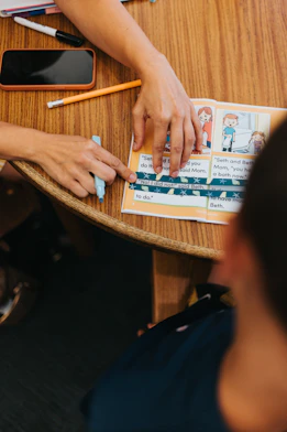 Adult helping a child read a book