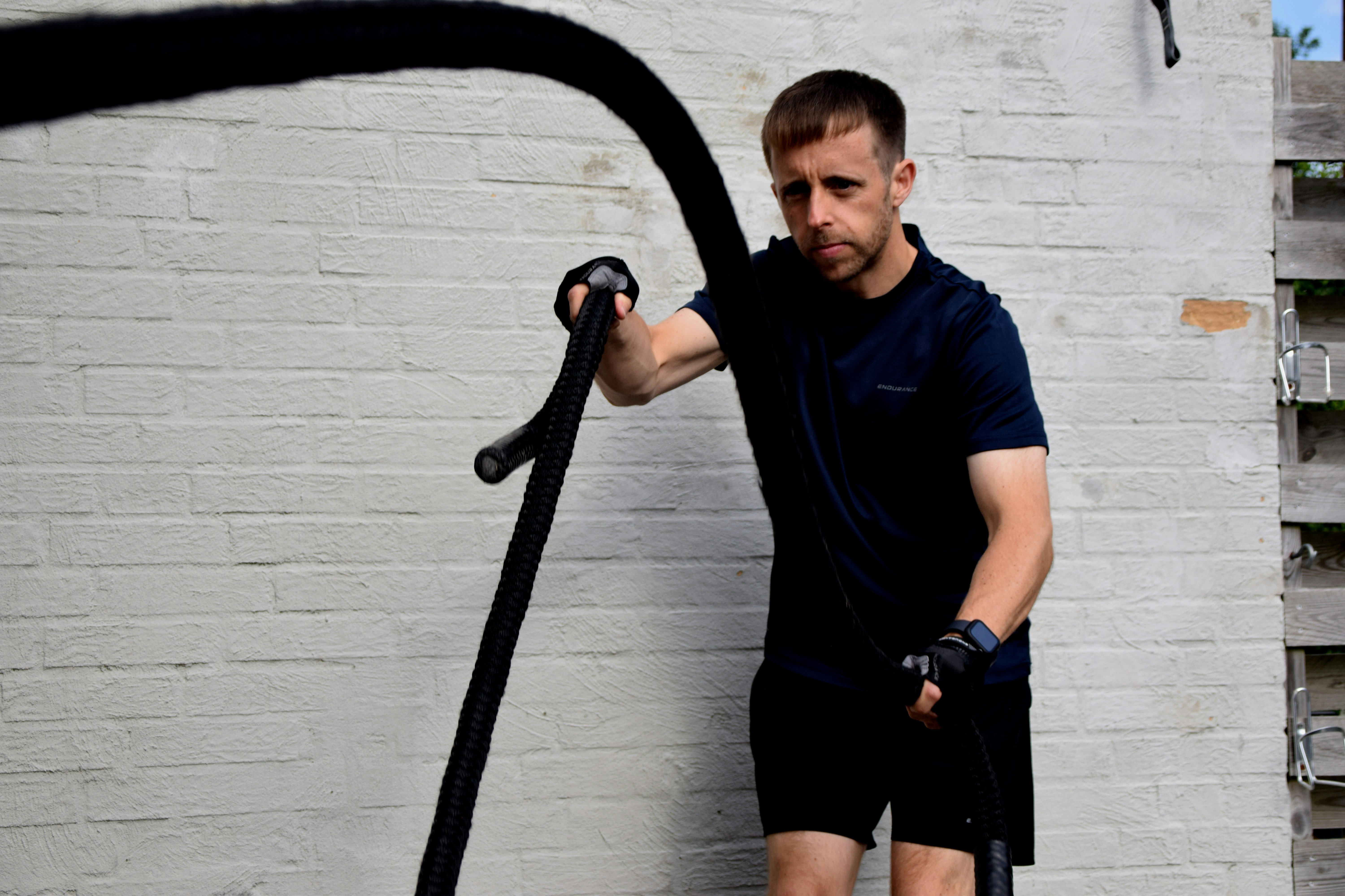 Man intensely exercising with battle ropes outdoors