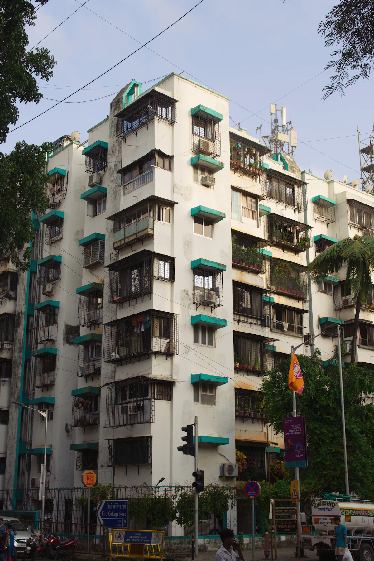 A white residential building in Mumbai with green window awnings