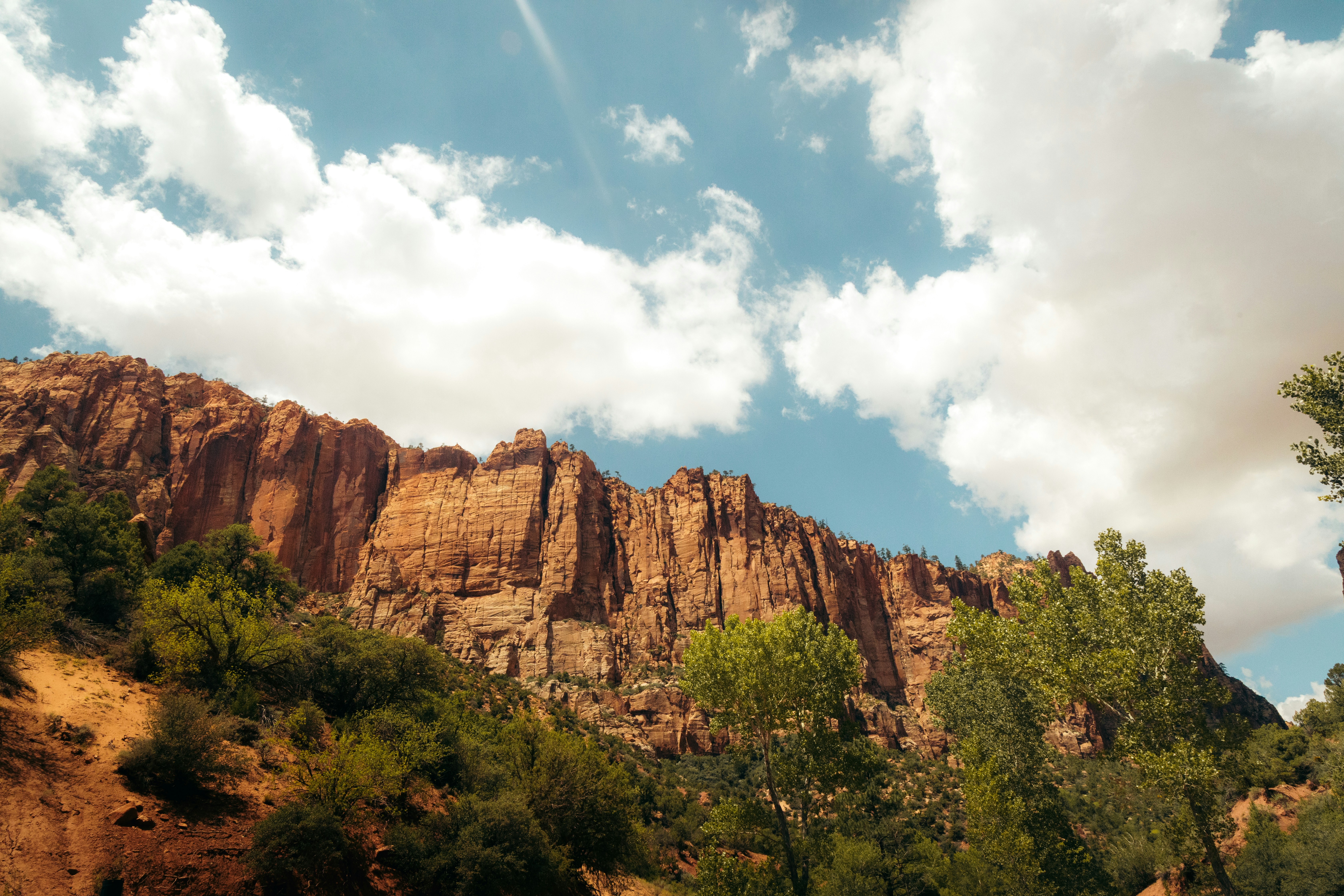 Formation rocheuse rouge avec arbres verts, ciel nuageux