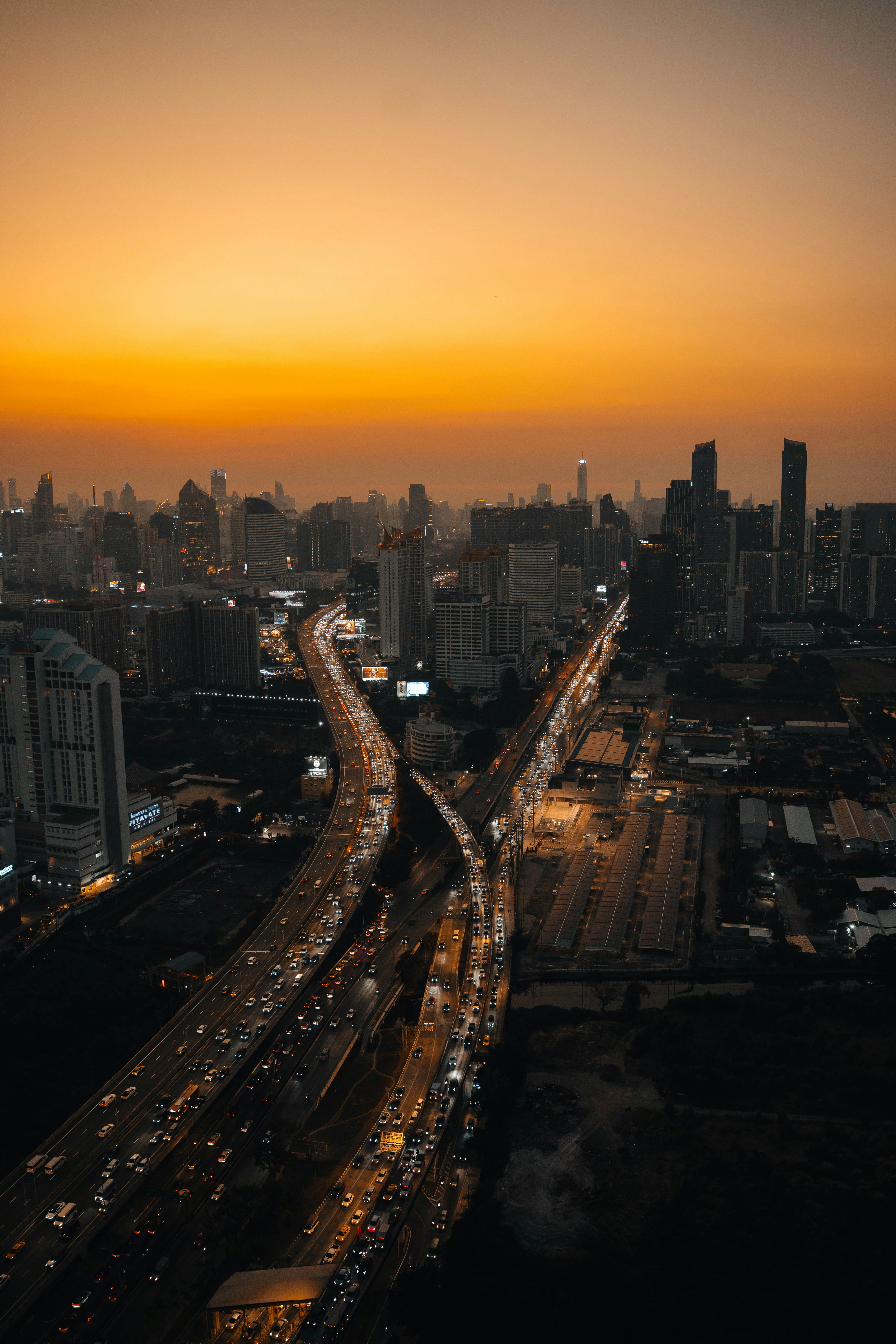Traffic-filled highways crisscross a city at golden hour.