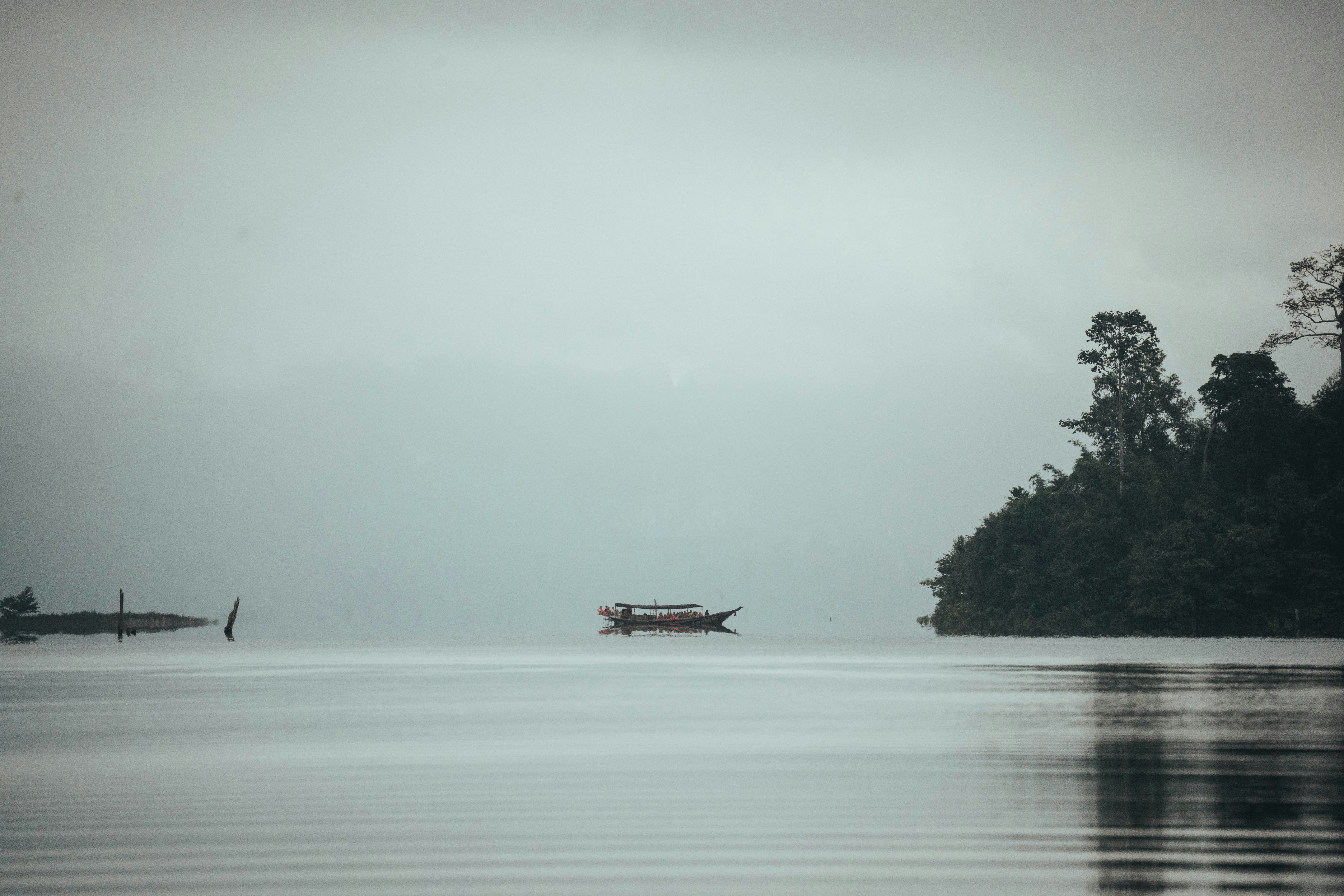 A boat on calm water, misty sky, and distant island