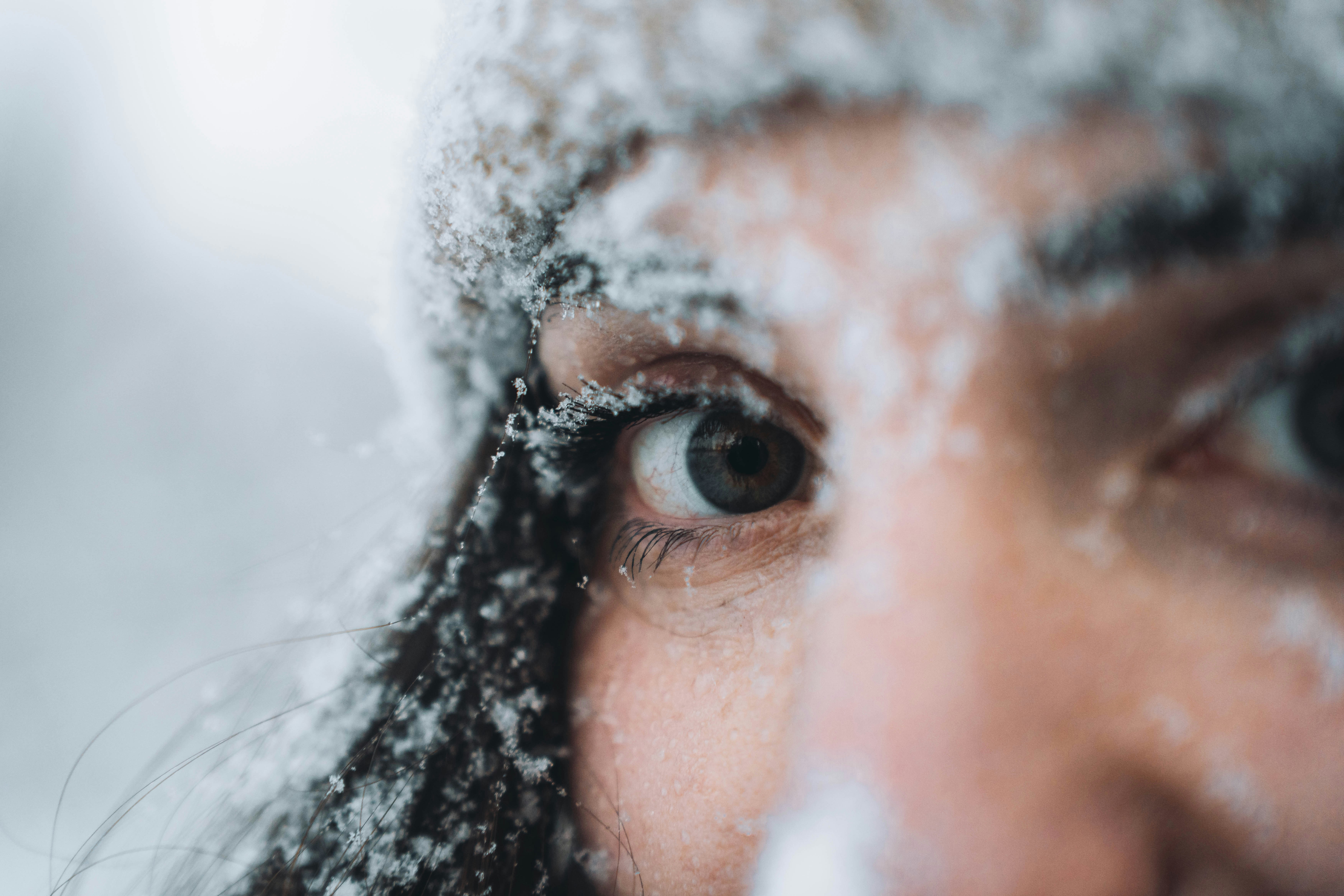 A person's eye and face covered in snow.