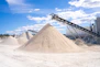Large sand and gravel piles with industrial conveyors
