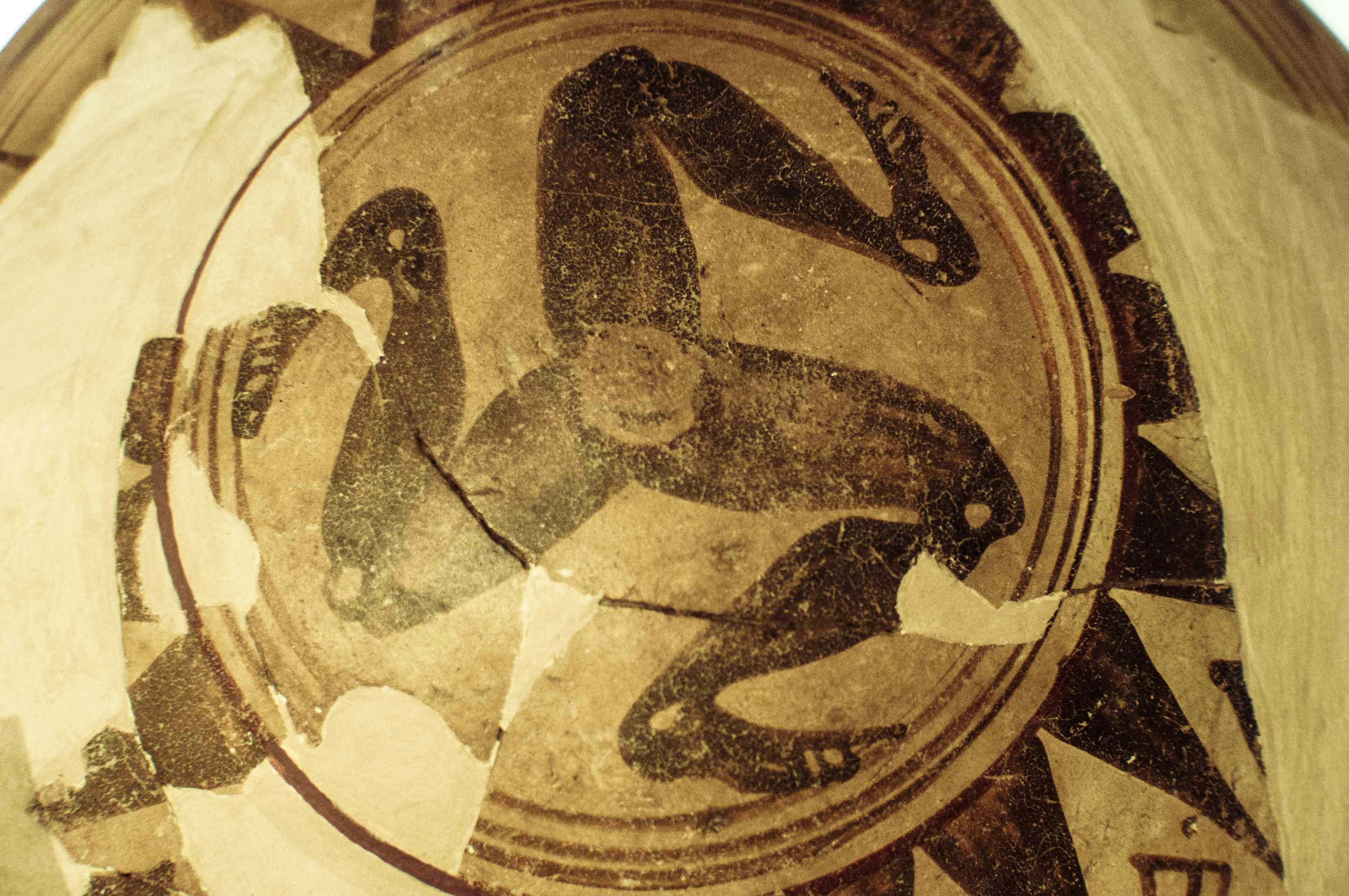 Ancient pottery fragment with a multi-legged figure design.