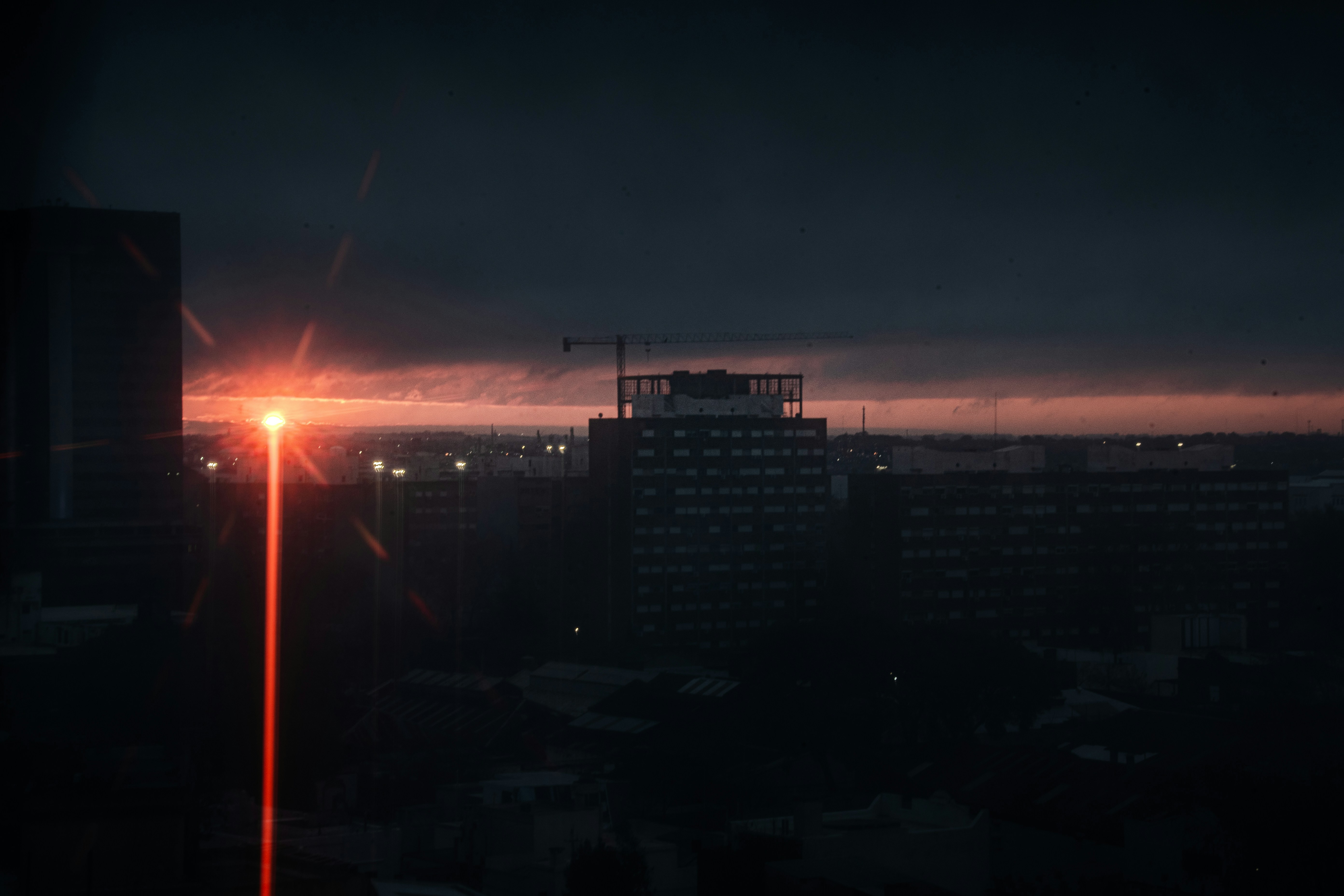 Dark cityscape at twilight with a prominent red light beam.