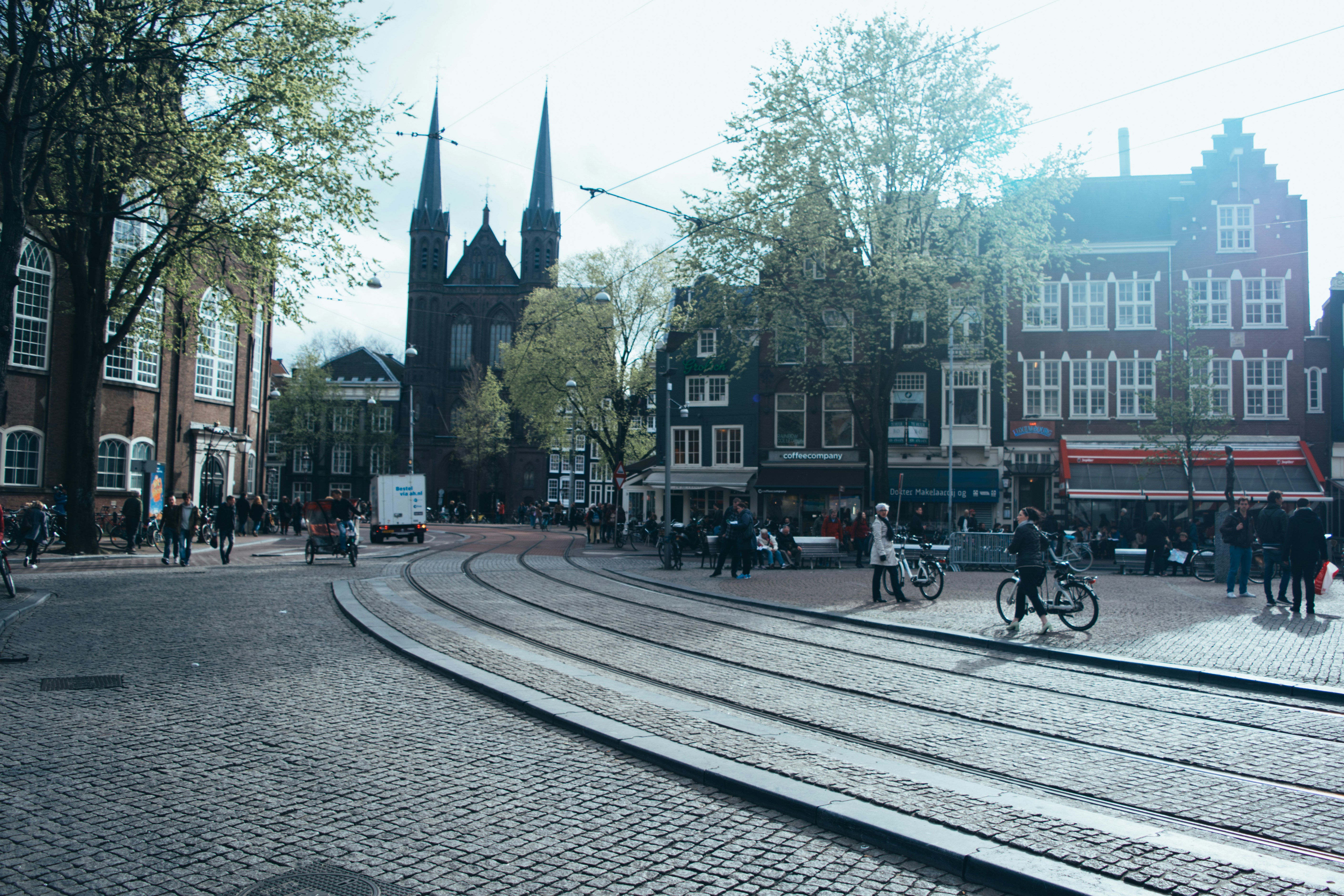 Historic city square with tram lines, people, and a church.