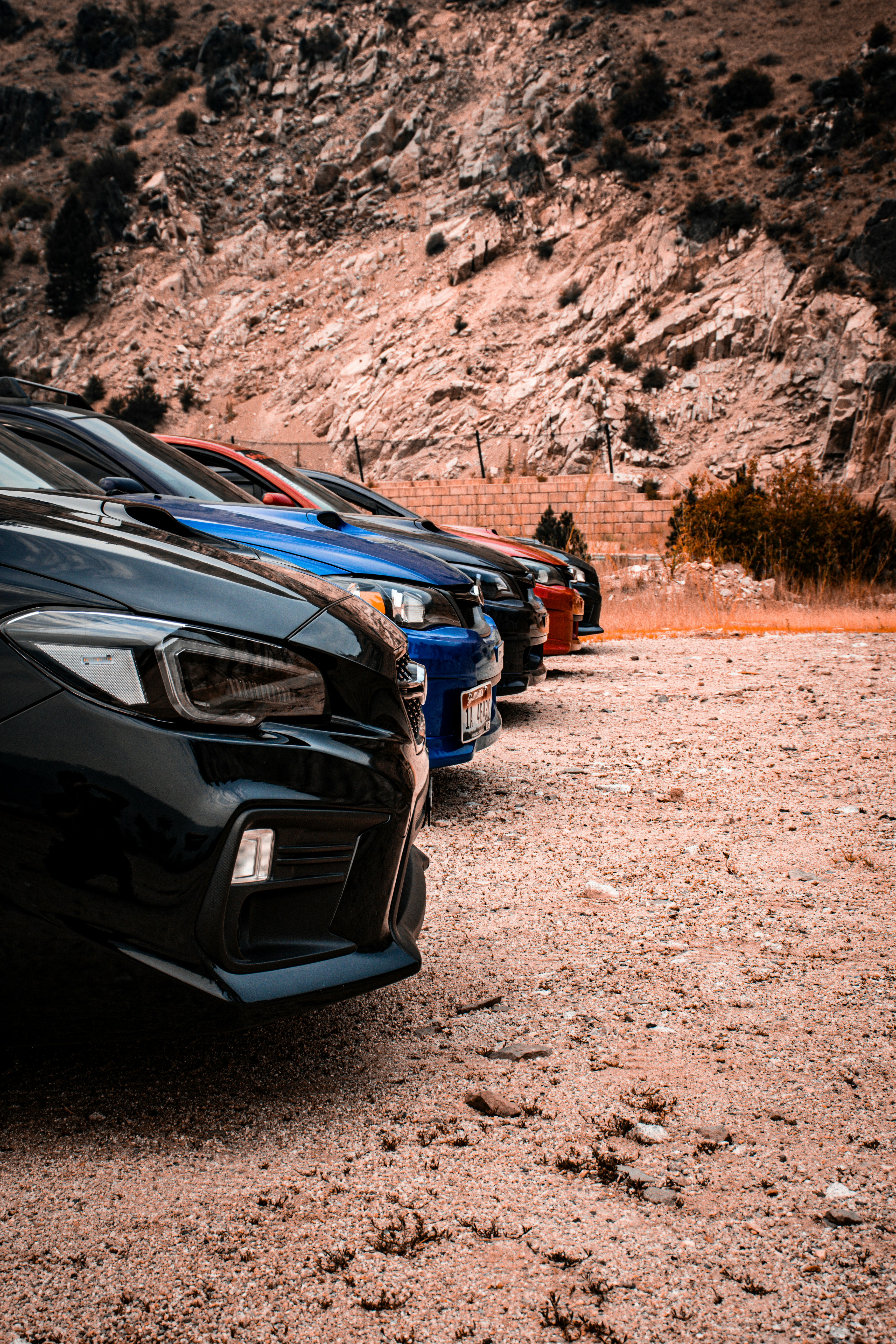 Los coches aparcaban en fila sobre tierra junto a las montañas rocosas.