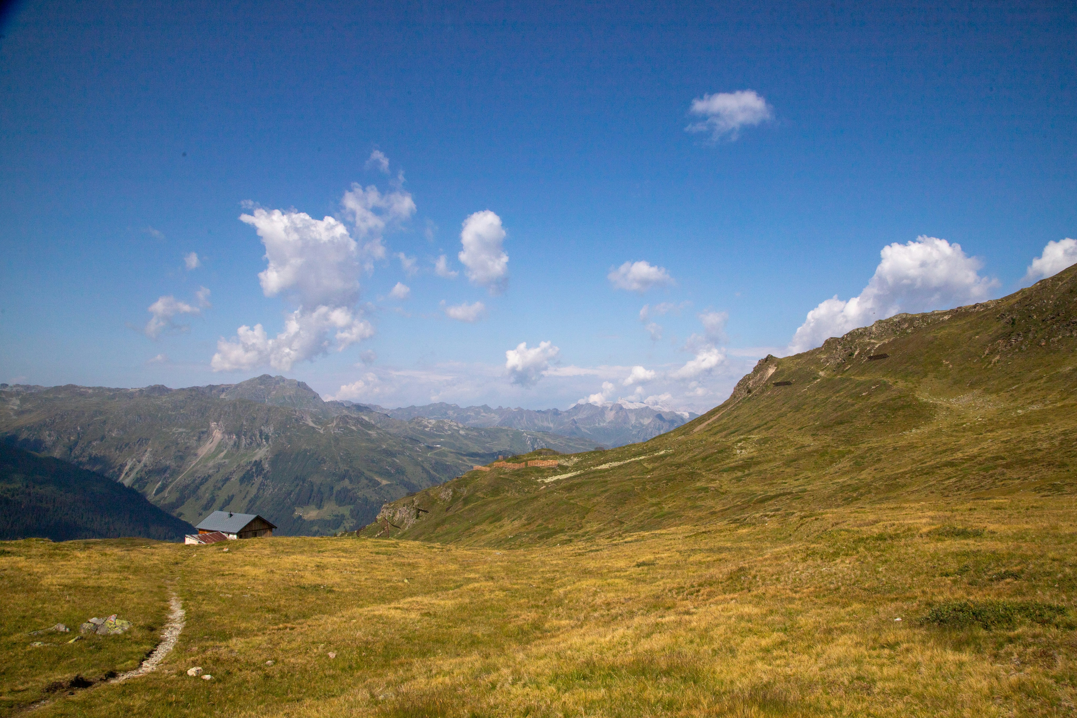 Golden grassy mountain landscape with a distant building.