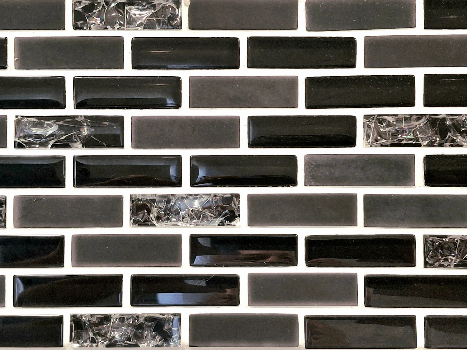 A wall of dark glazed brick tiles with pale grout running between them
