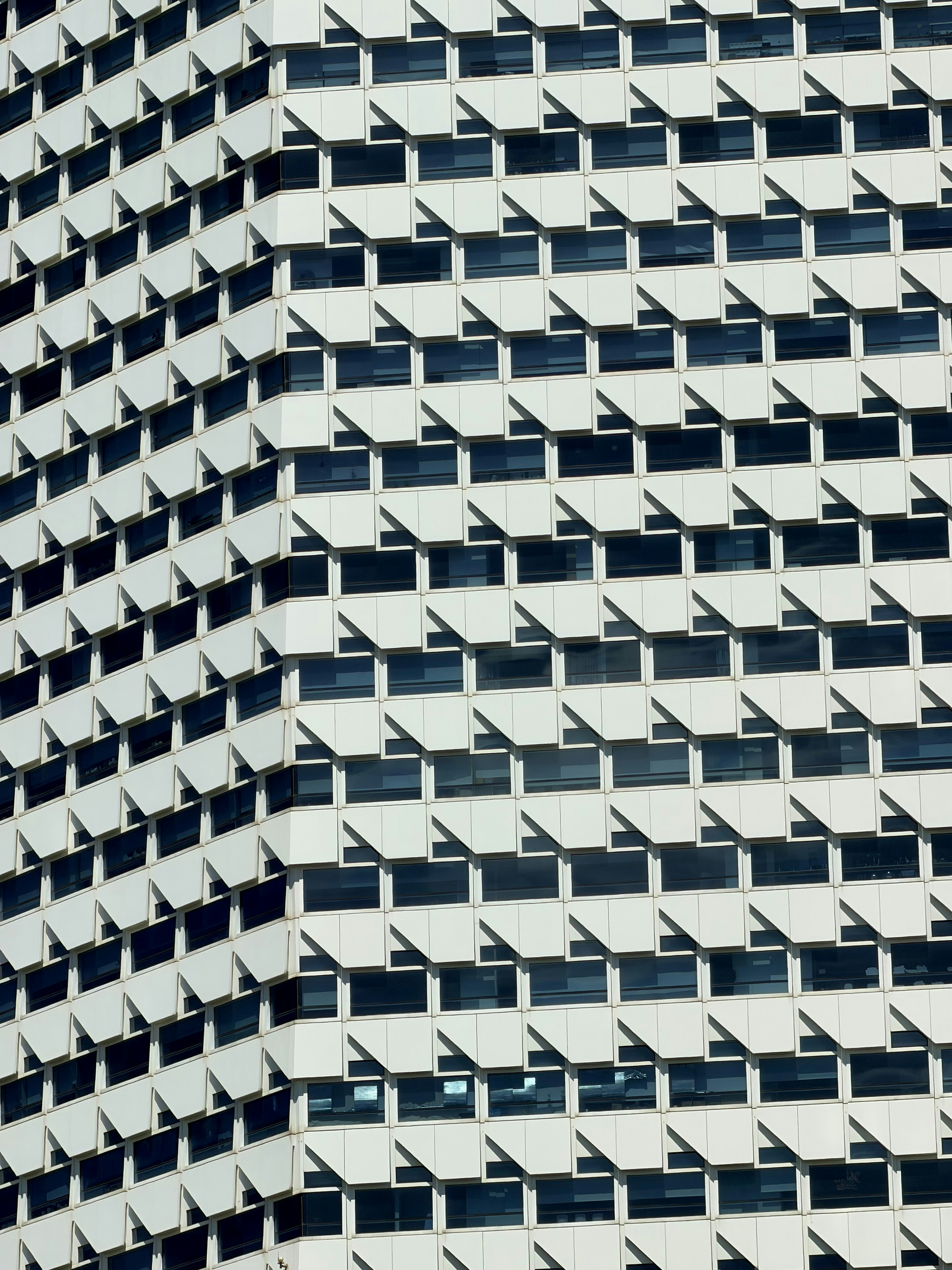 Modern building facade with repeating white panels and dark windows.