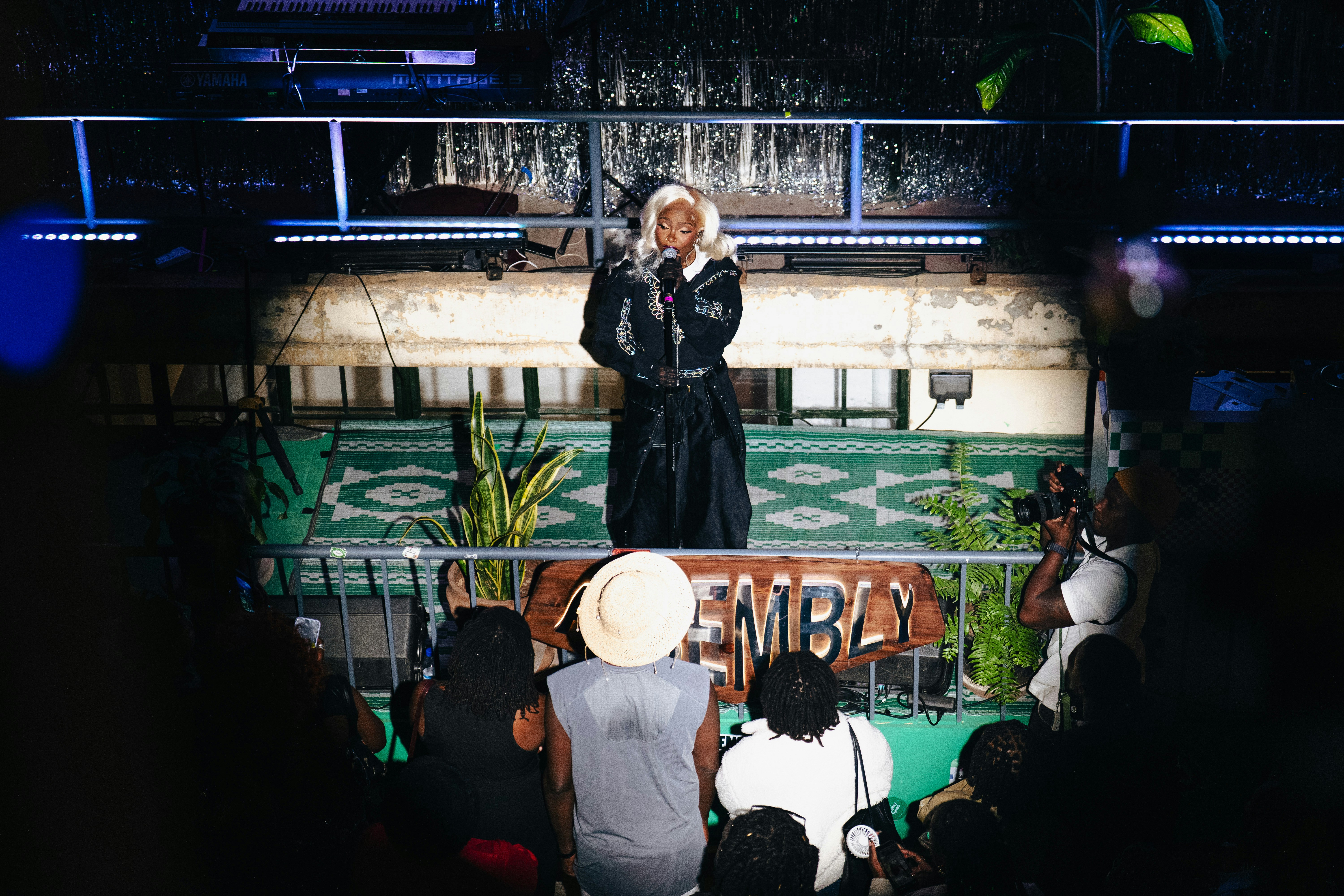 A person performs on stage for an audience at night.