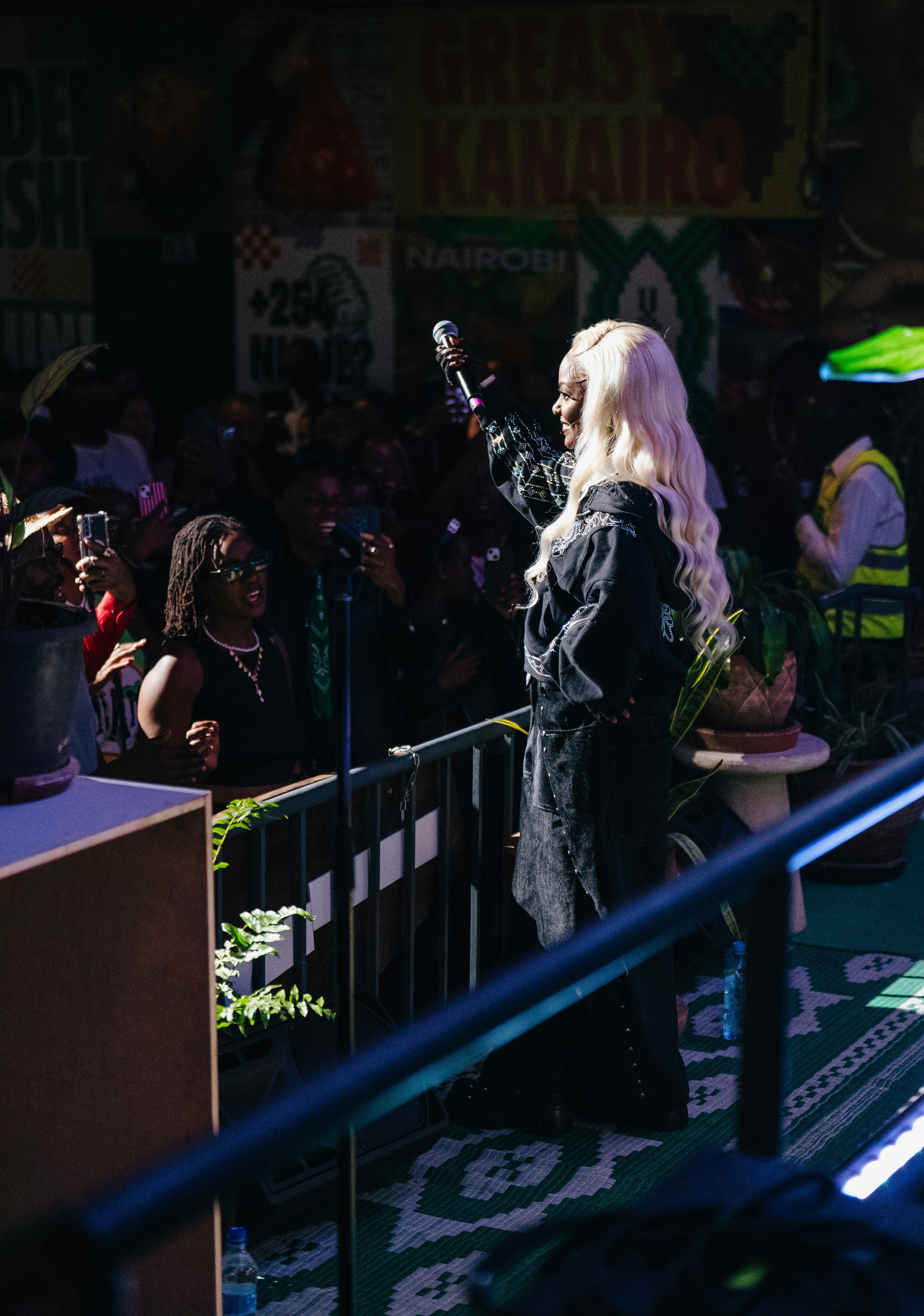 Performer with long blonde hair sings into a microphone.
