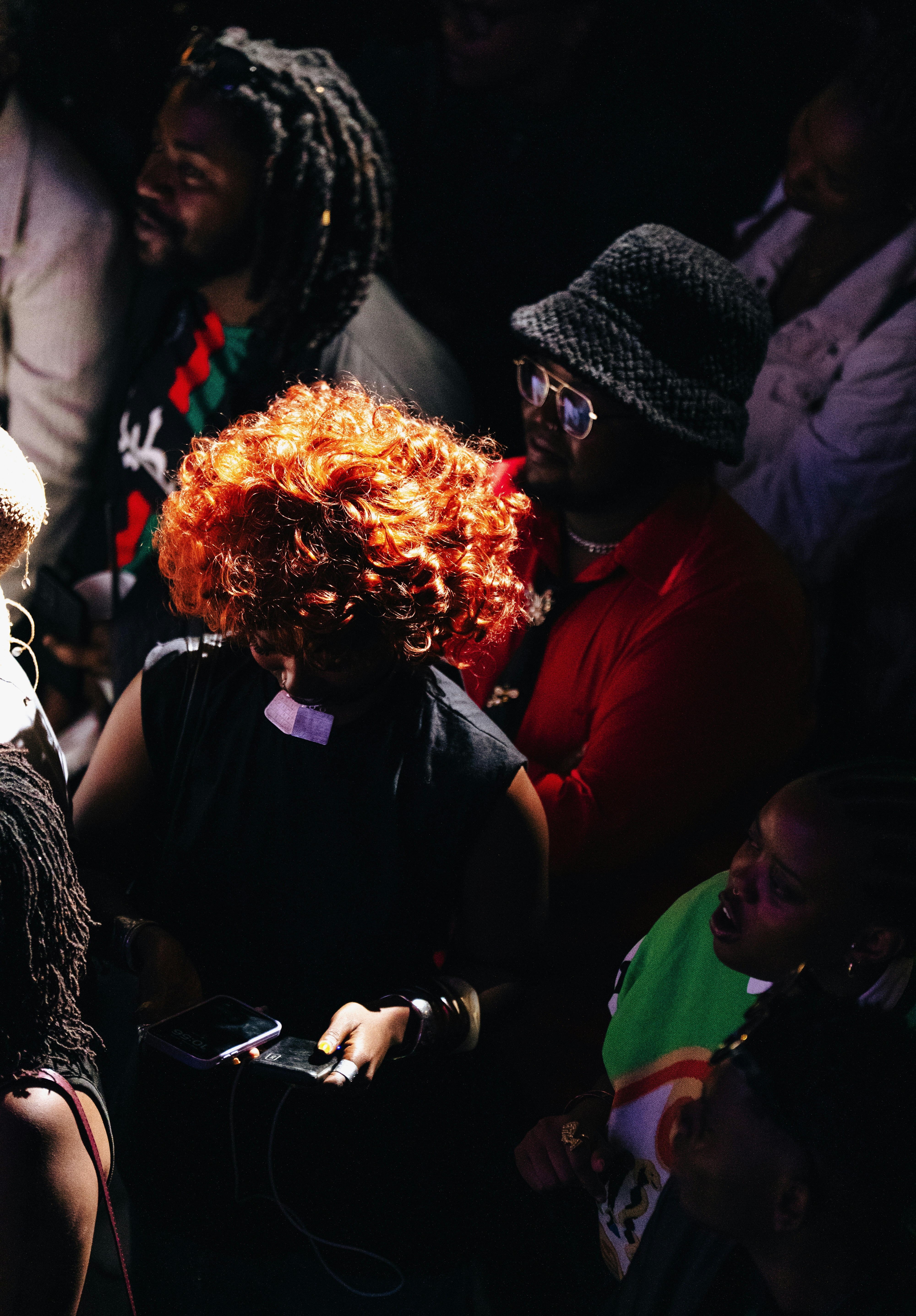 A crowd of people, one with bright red curly hair.