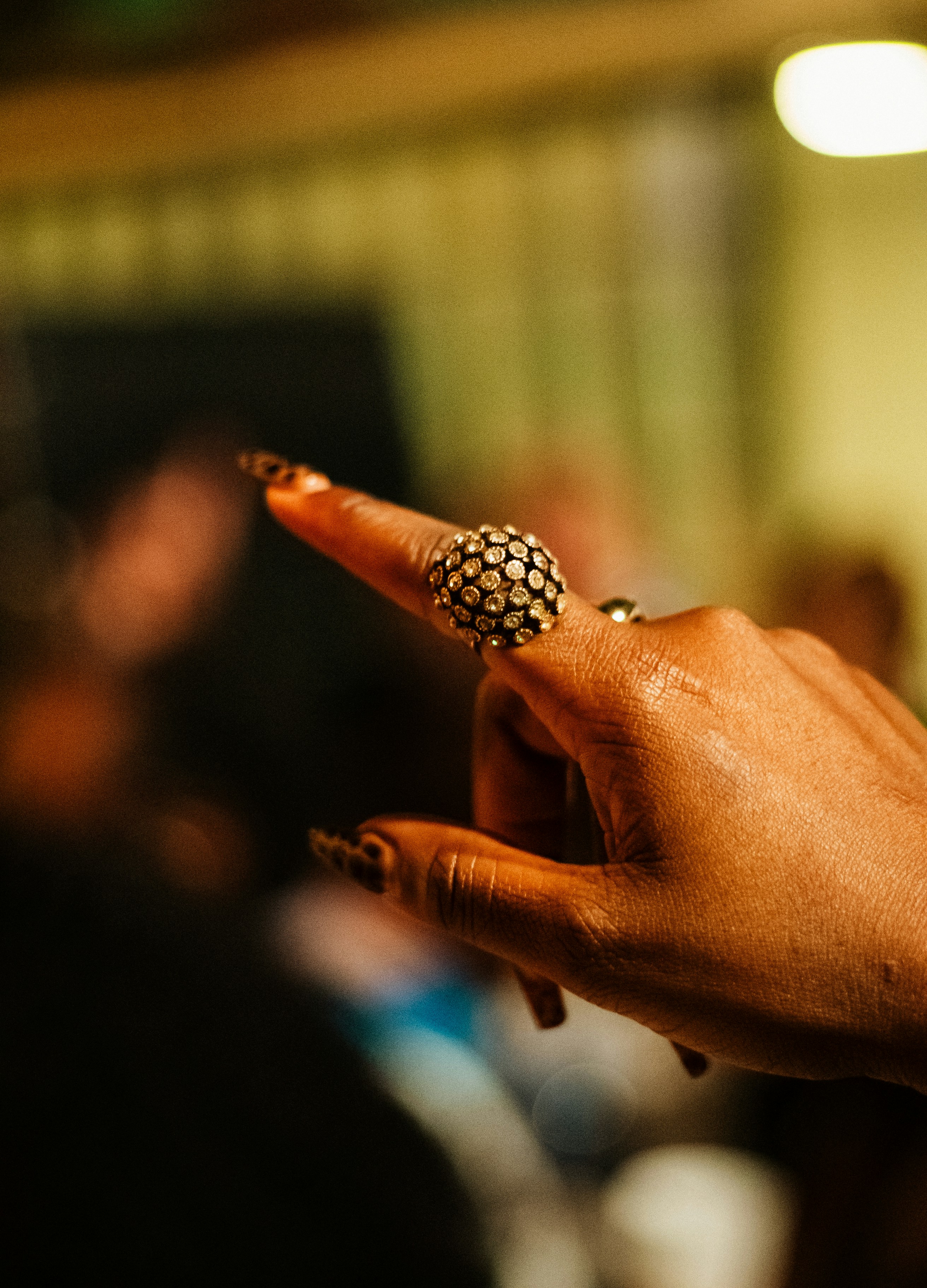 Ornate ring on a finger with long dark nails.