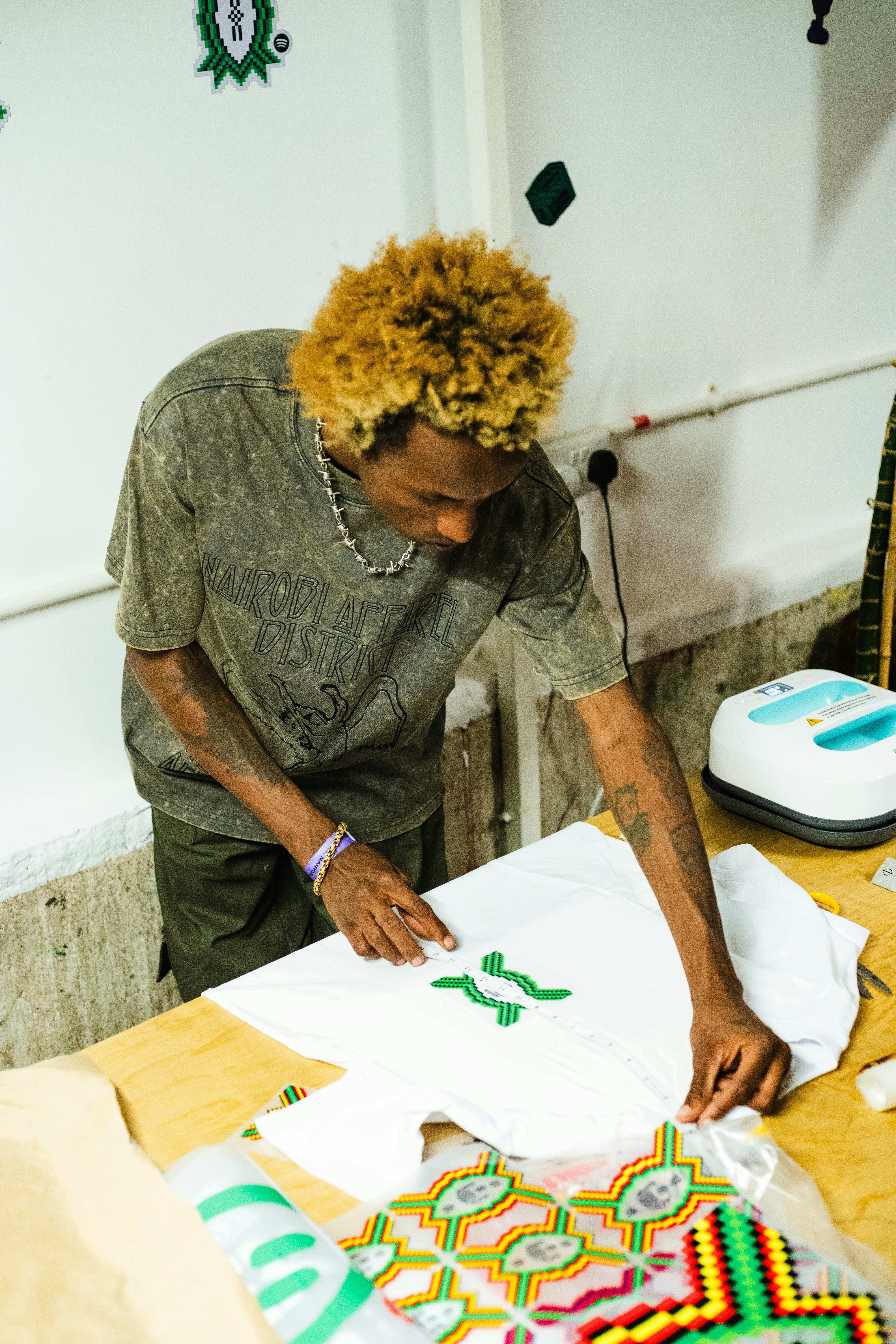 Young man applying a green design to a white t-shirt