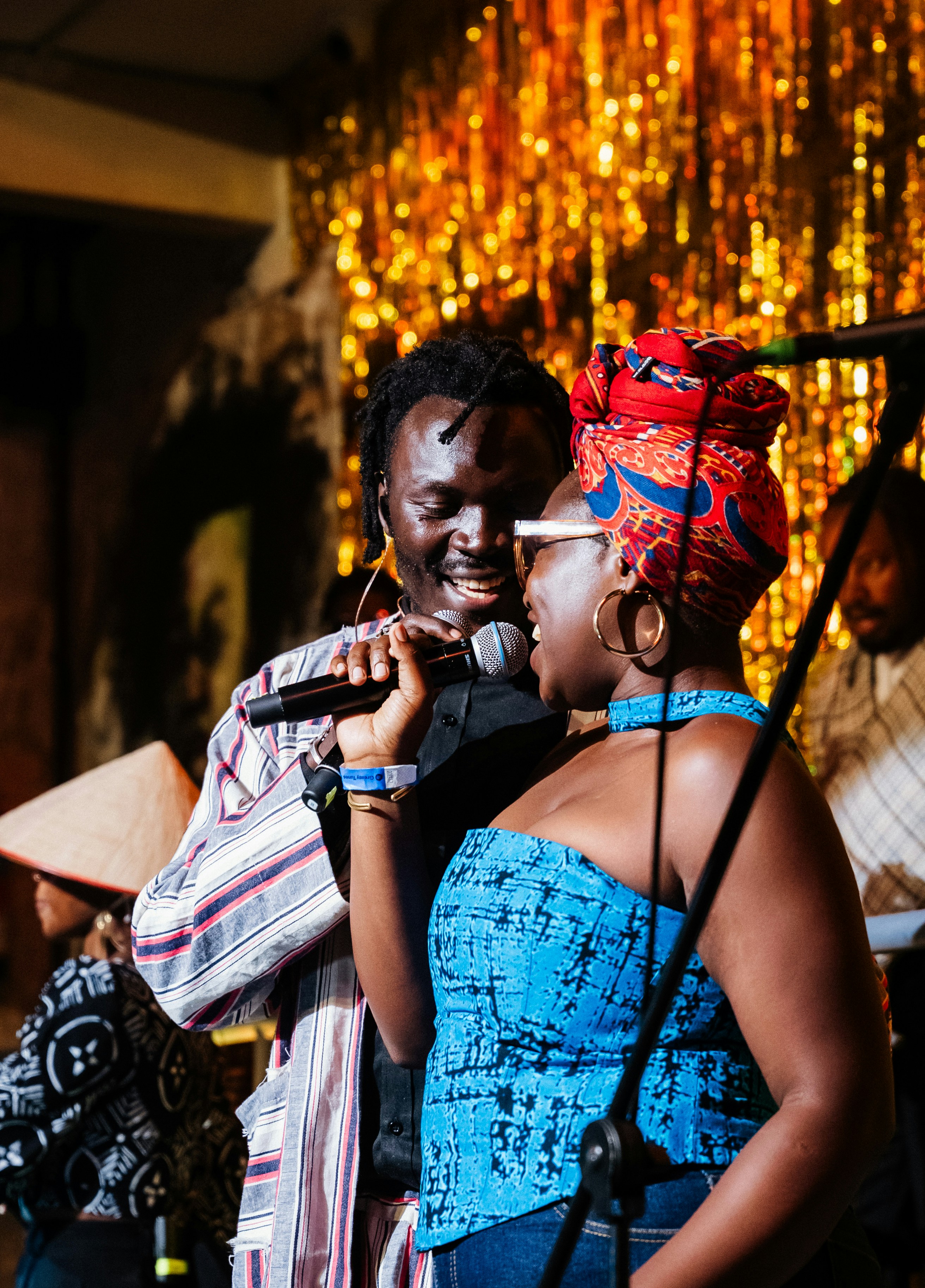 Man and woman singing together on stage with a microphone.