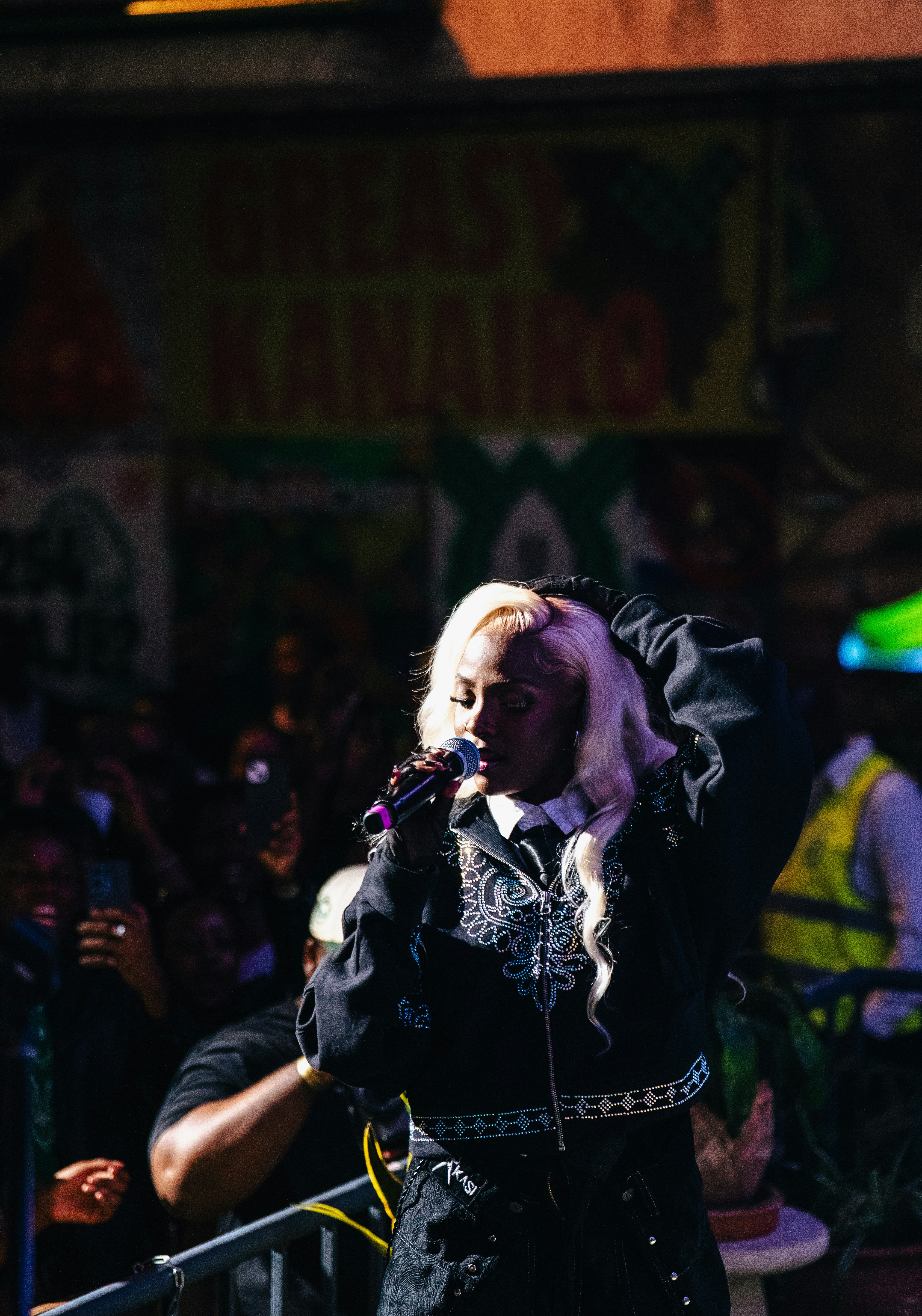 Blonde woman singing into microphone on stage.