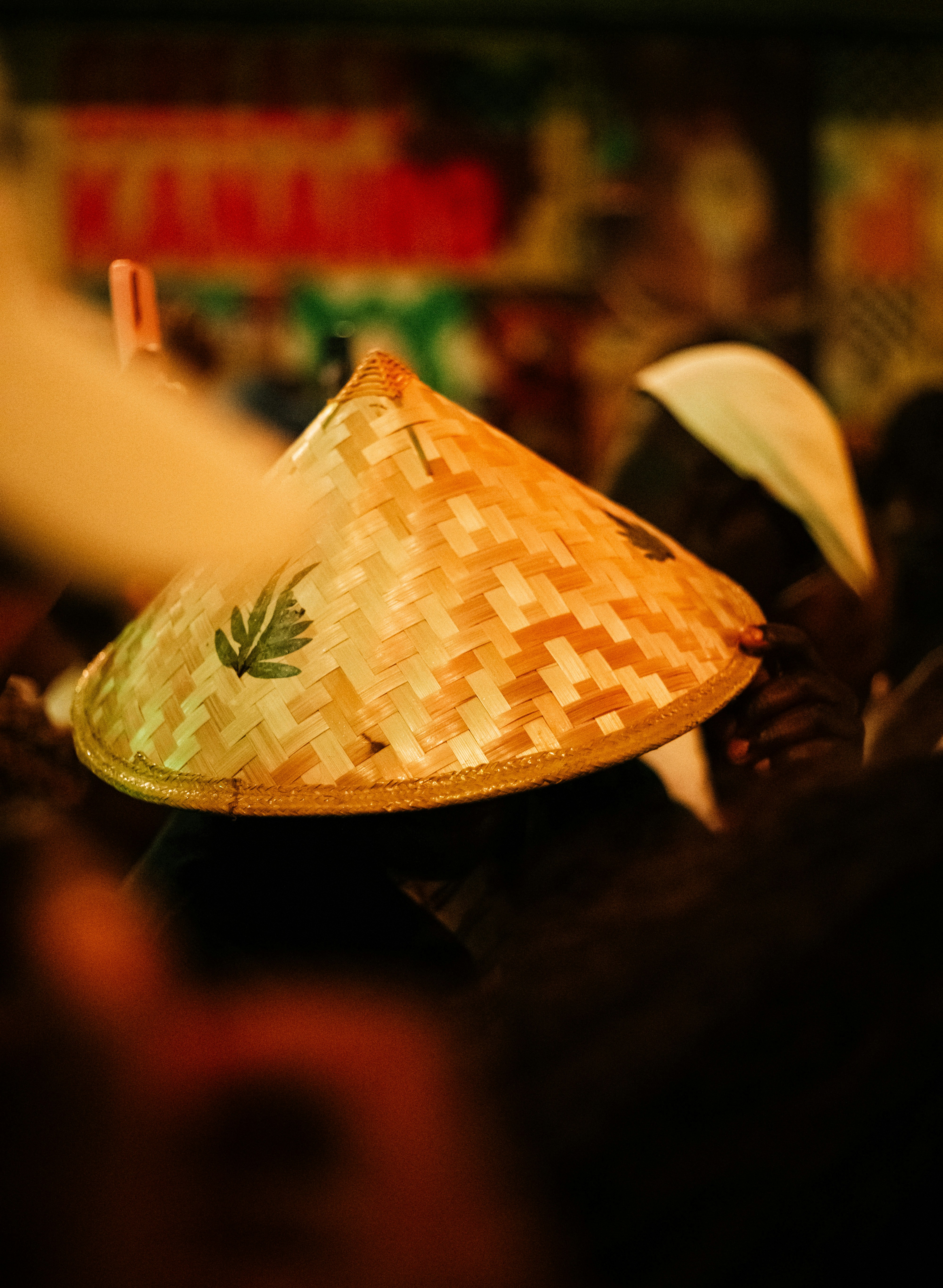 A conical straw hat with a green leaf design.
