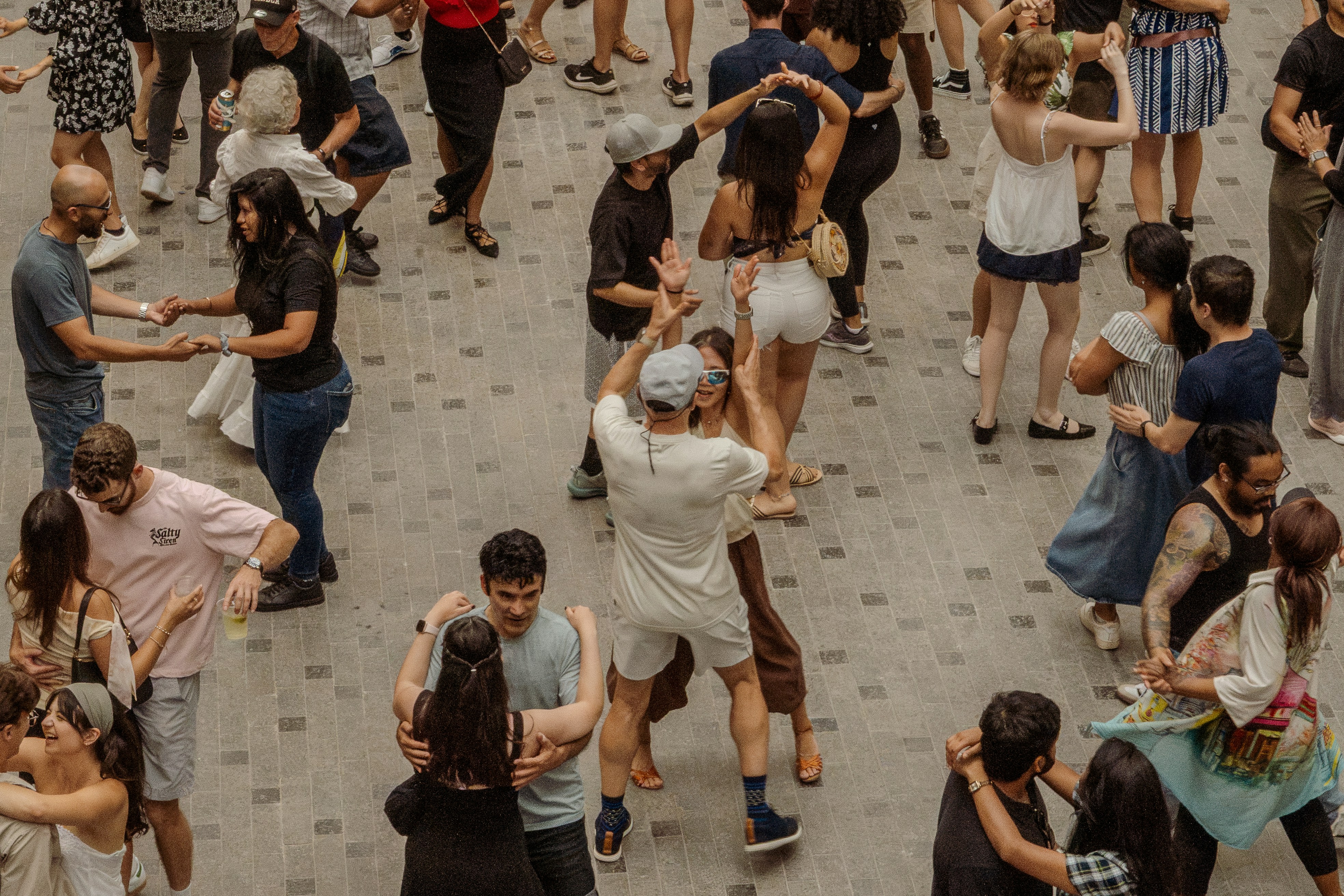Many people dancing together outdoors in a public square