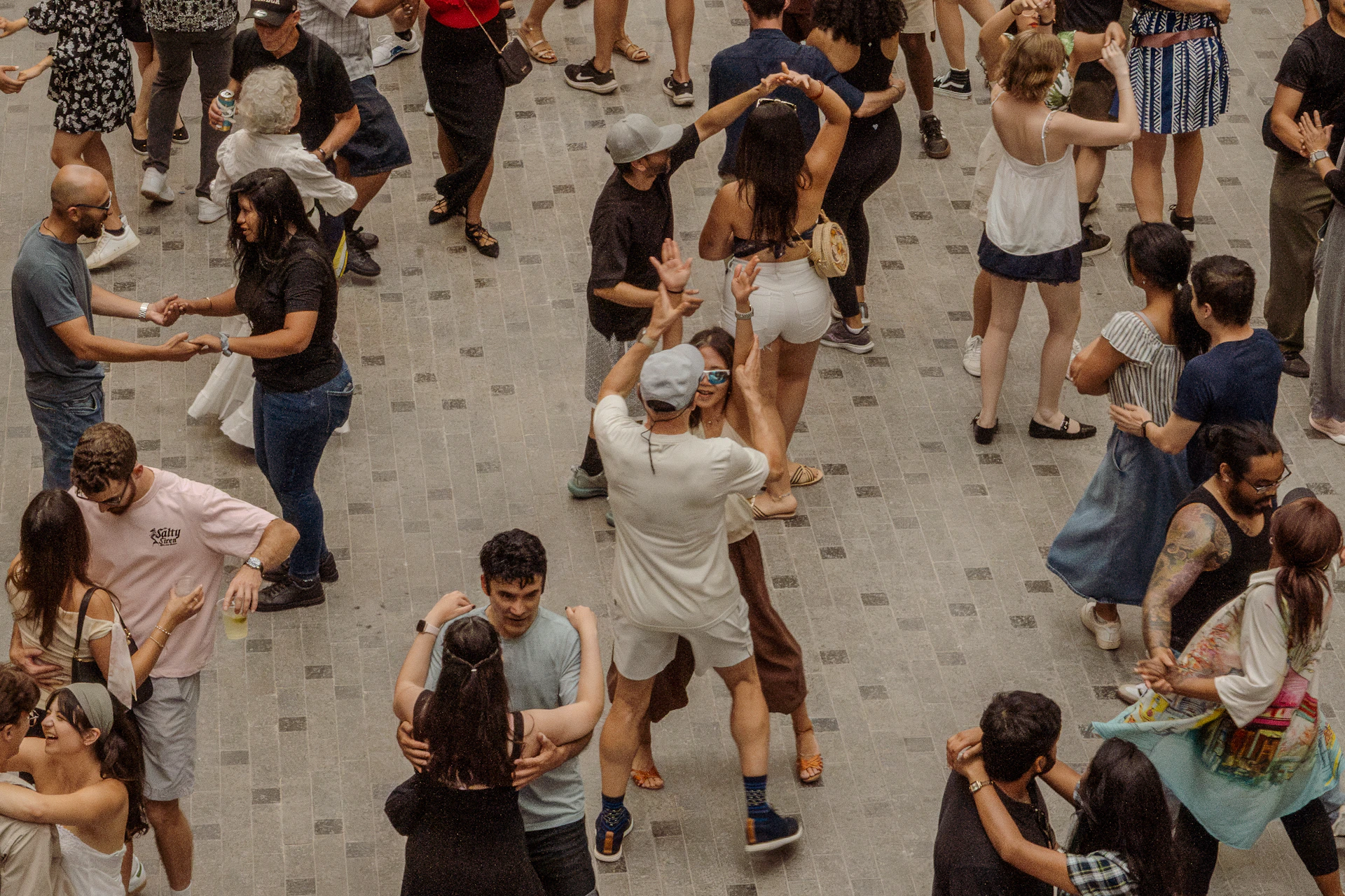 Many people dancing together outdoors in a public square