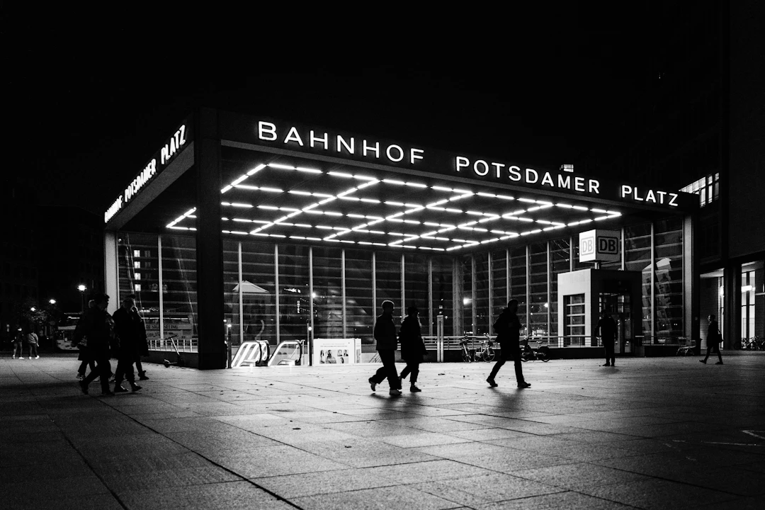 Potsdamer Platz station in Berlin lit up at night with people walking past